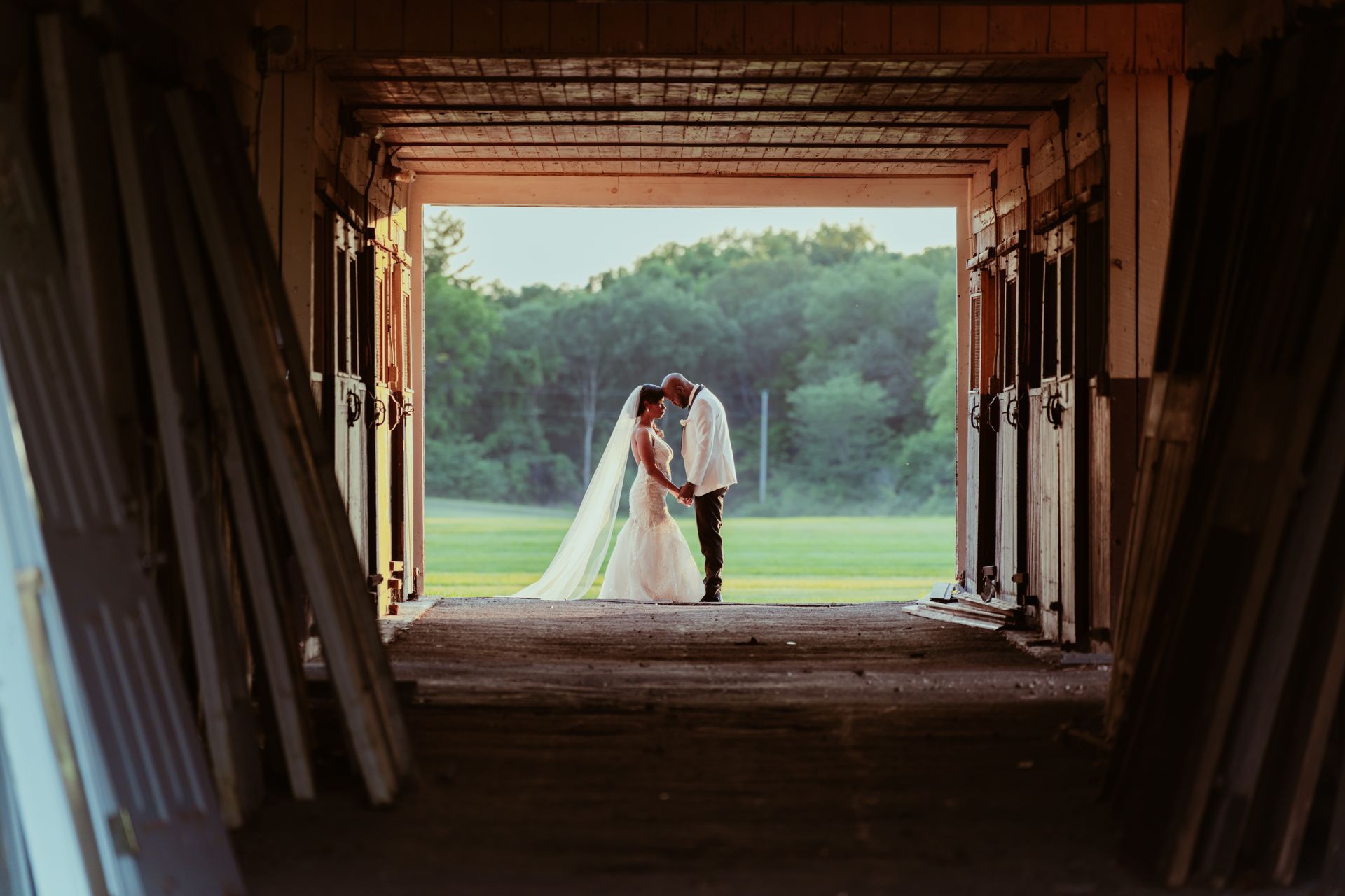 A bride and groom are kissing in a barn at the Darby House.