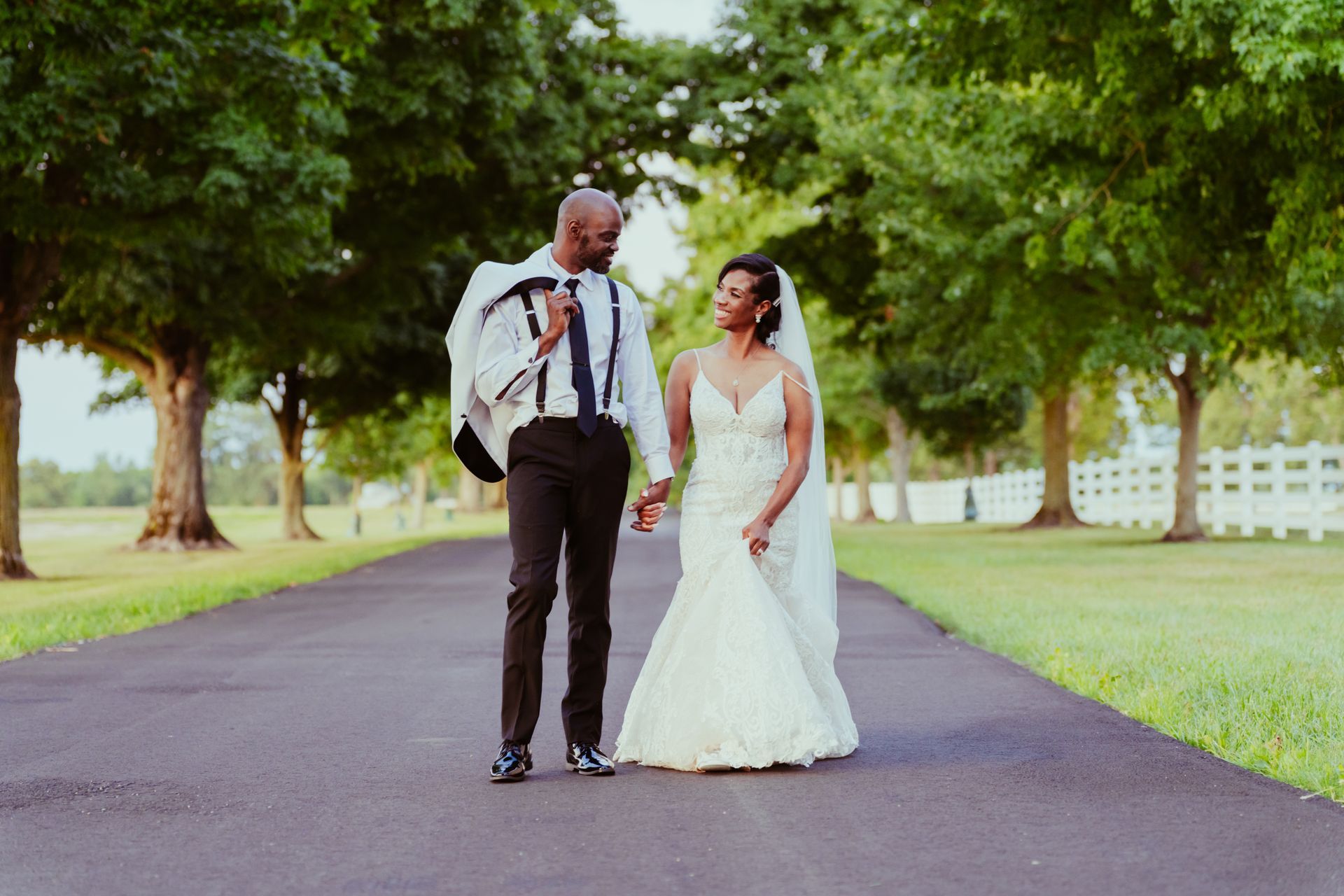 A bride and groom are walking down a path holding hands at Darby House