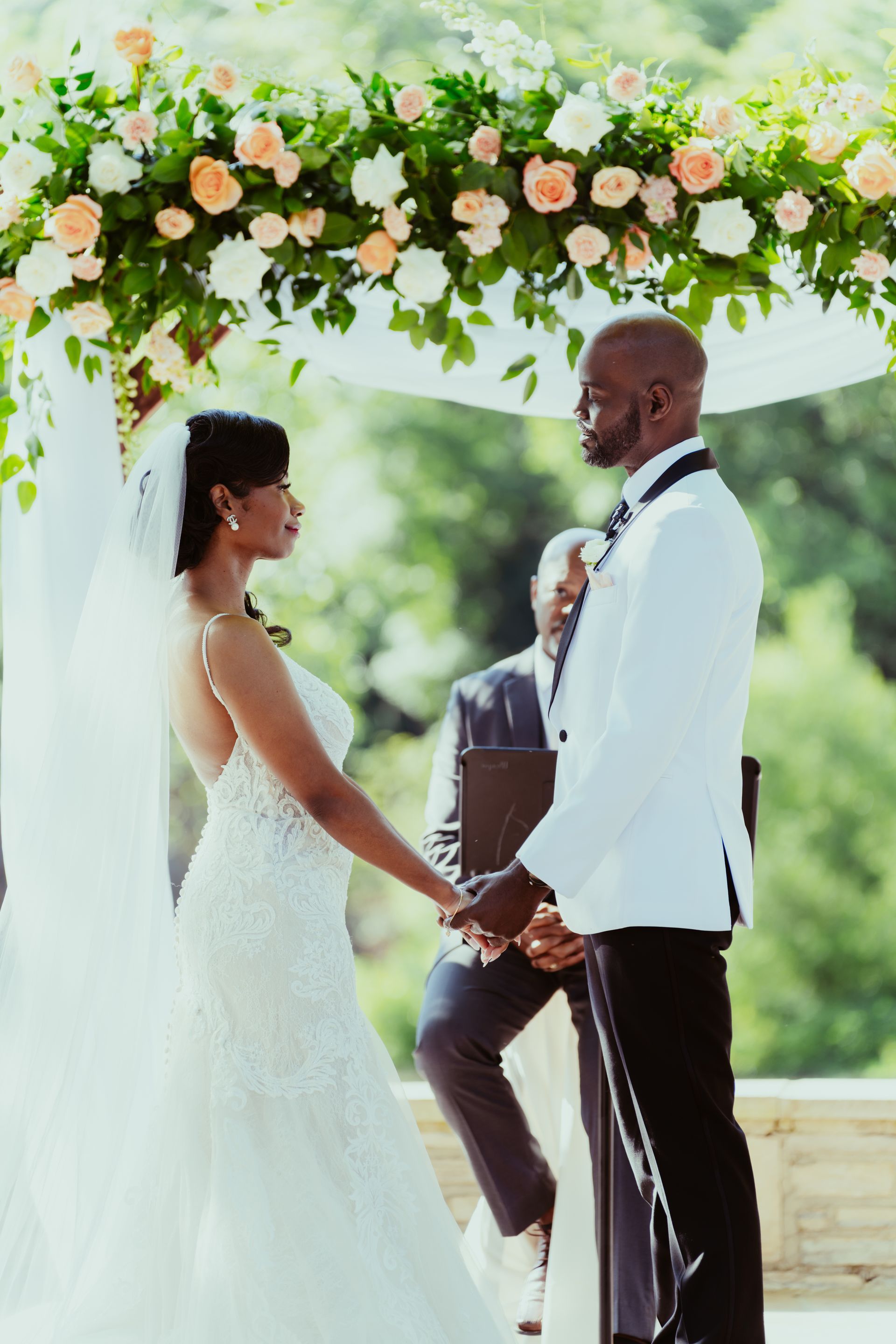 A bride and groom are holding hands during their wedding ceremony.