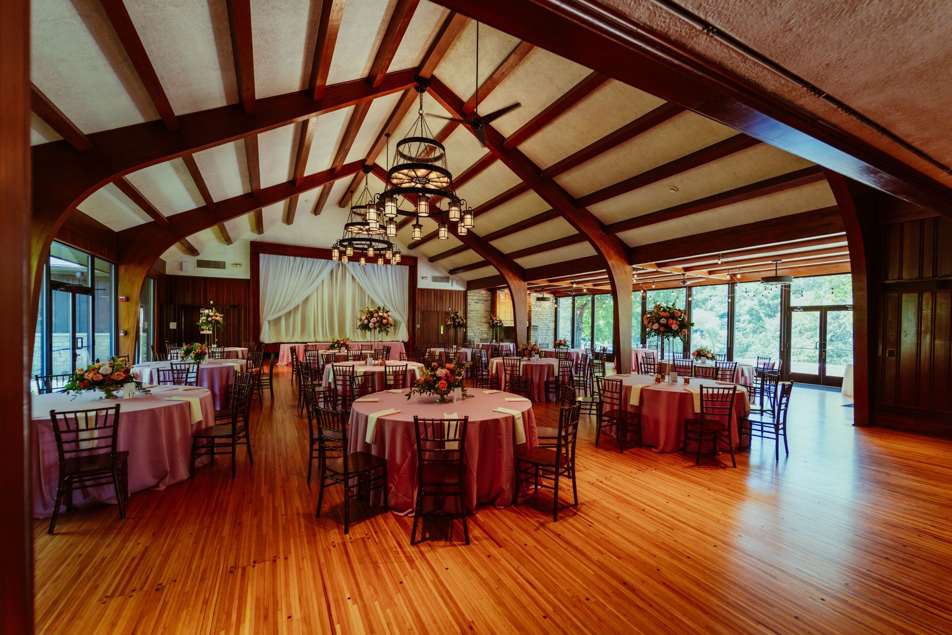 A large room with tables and chairs set up for a wedding reception
