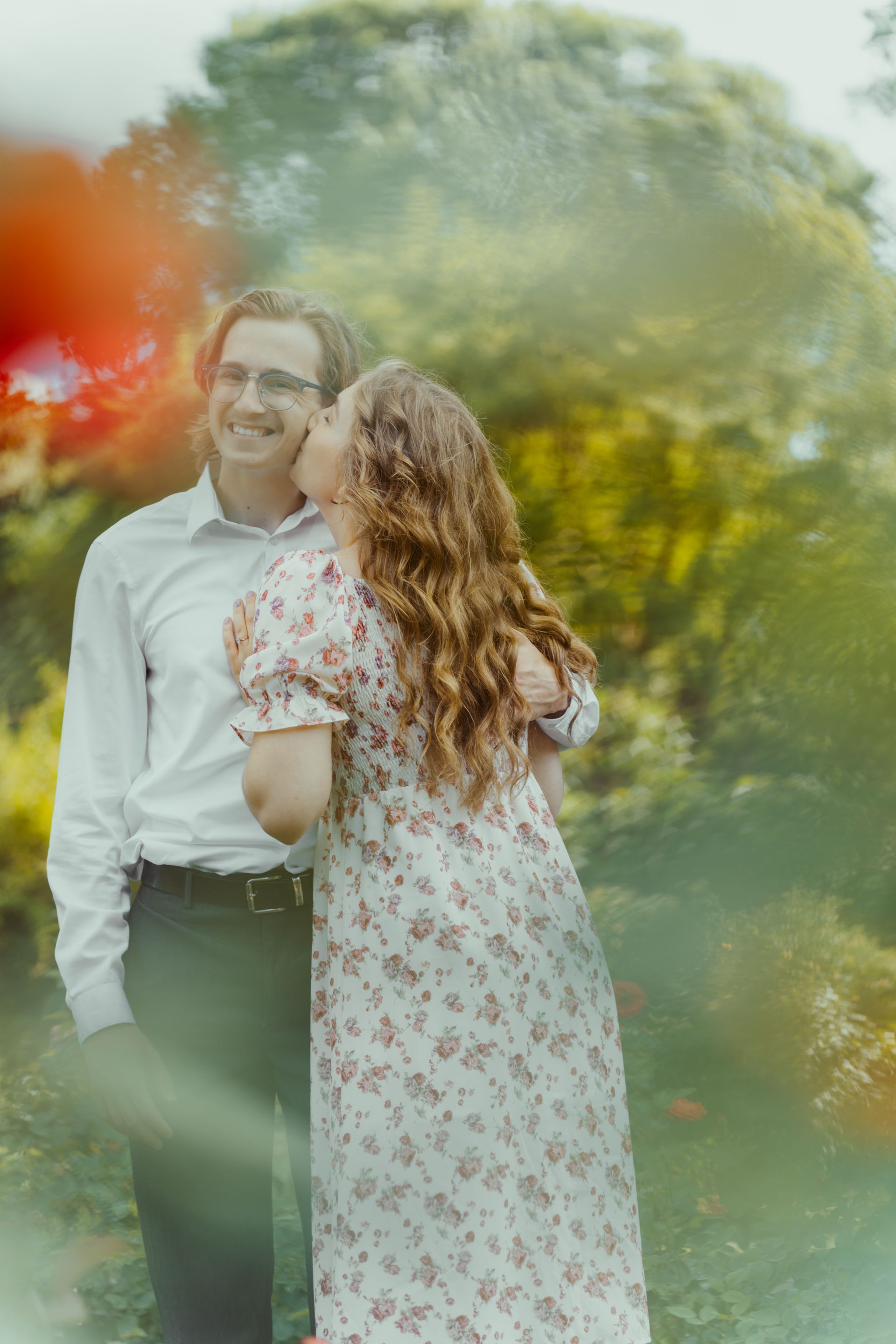 A man and a woman are standing next to each other in a park.