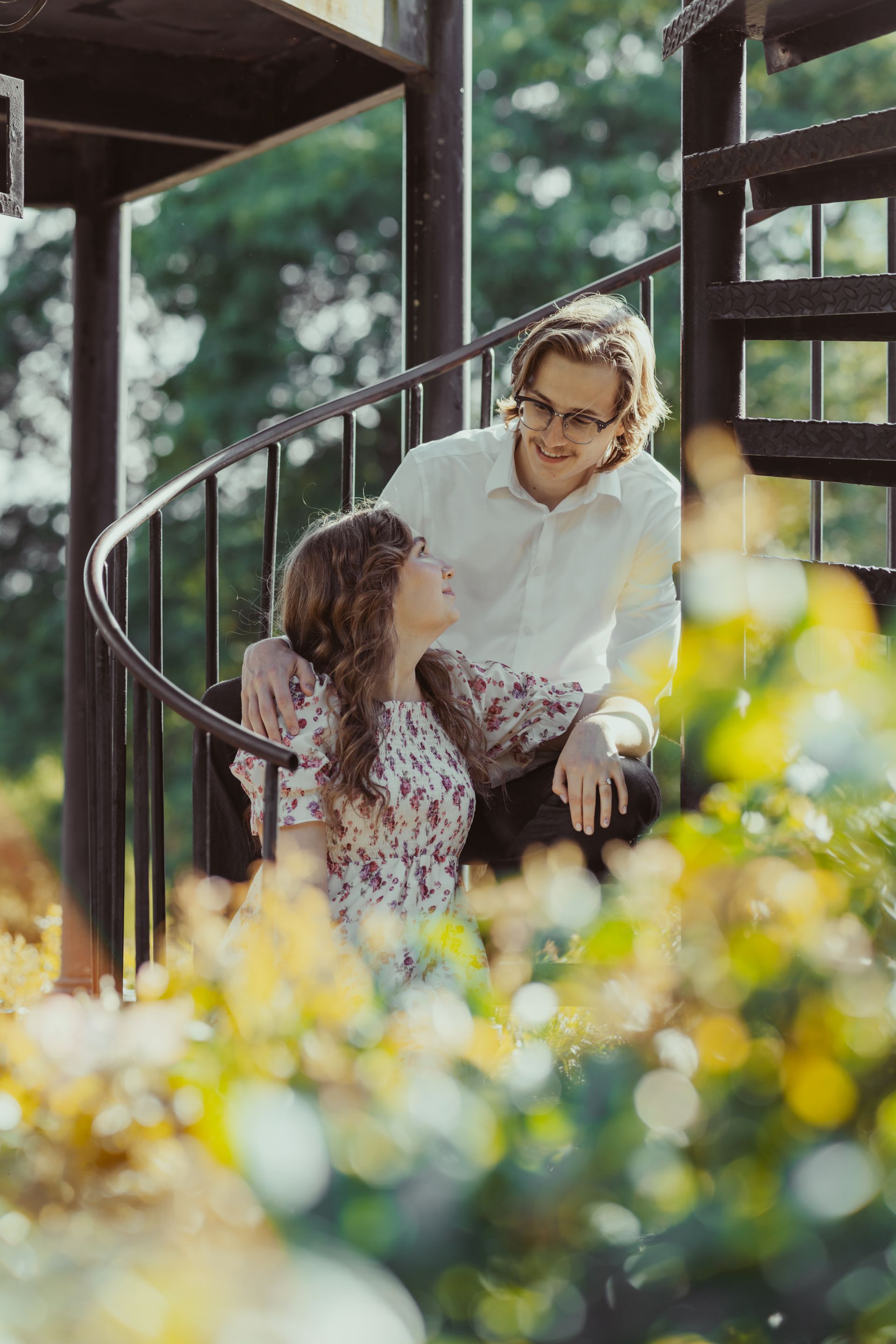 A man and a woman are sitting on a spiral staircase.