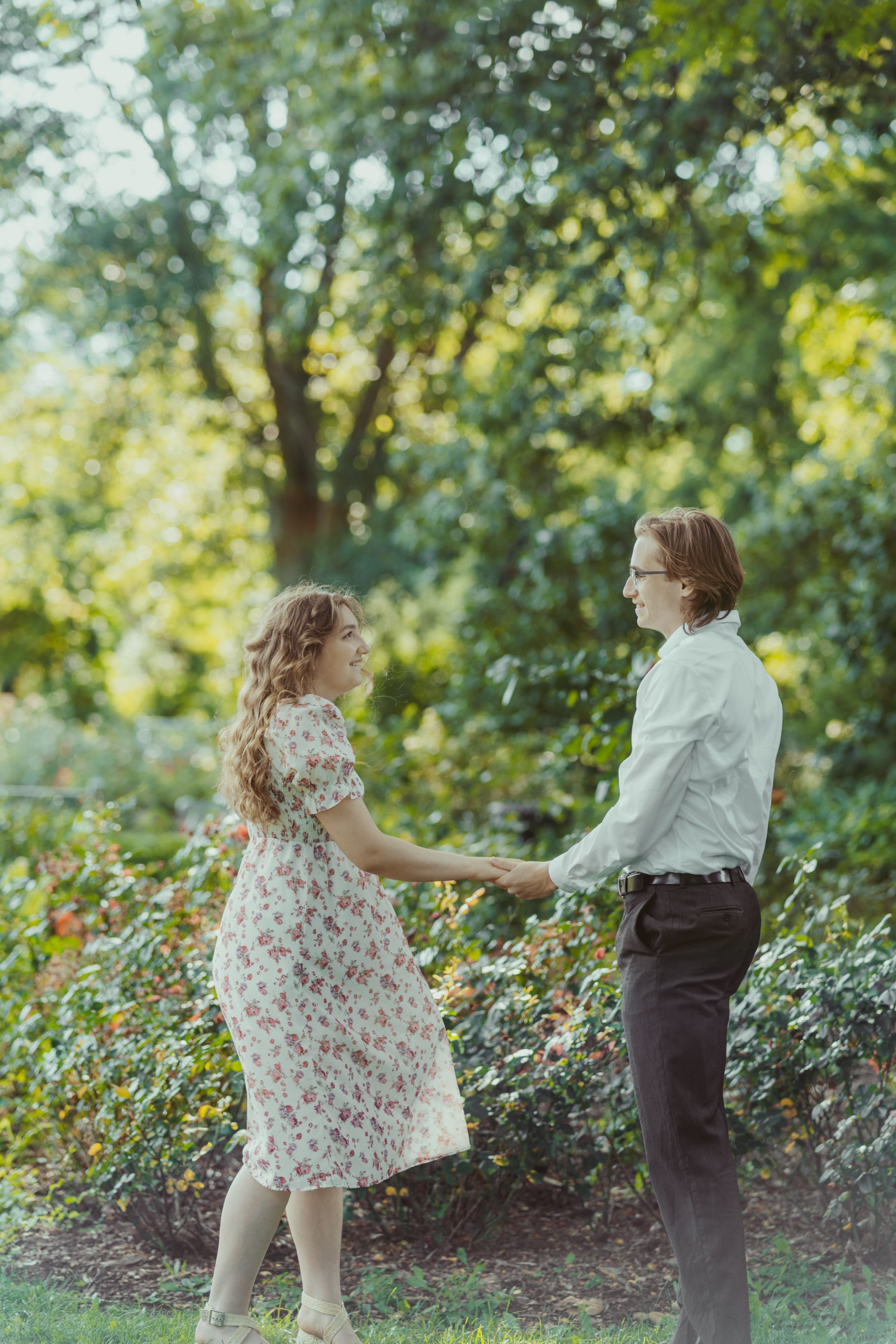 A man and a woman are holding hands in a park.