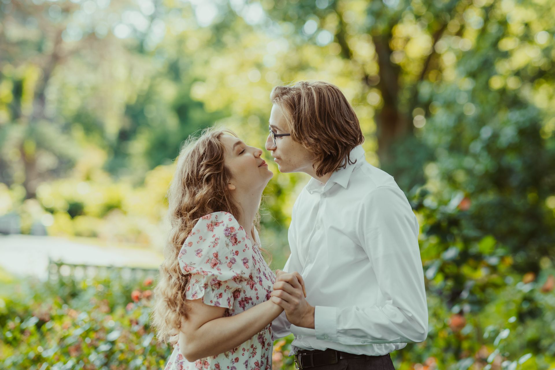 A man and a woman are kissing in a park.