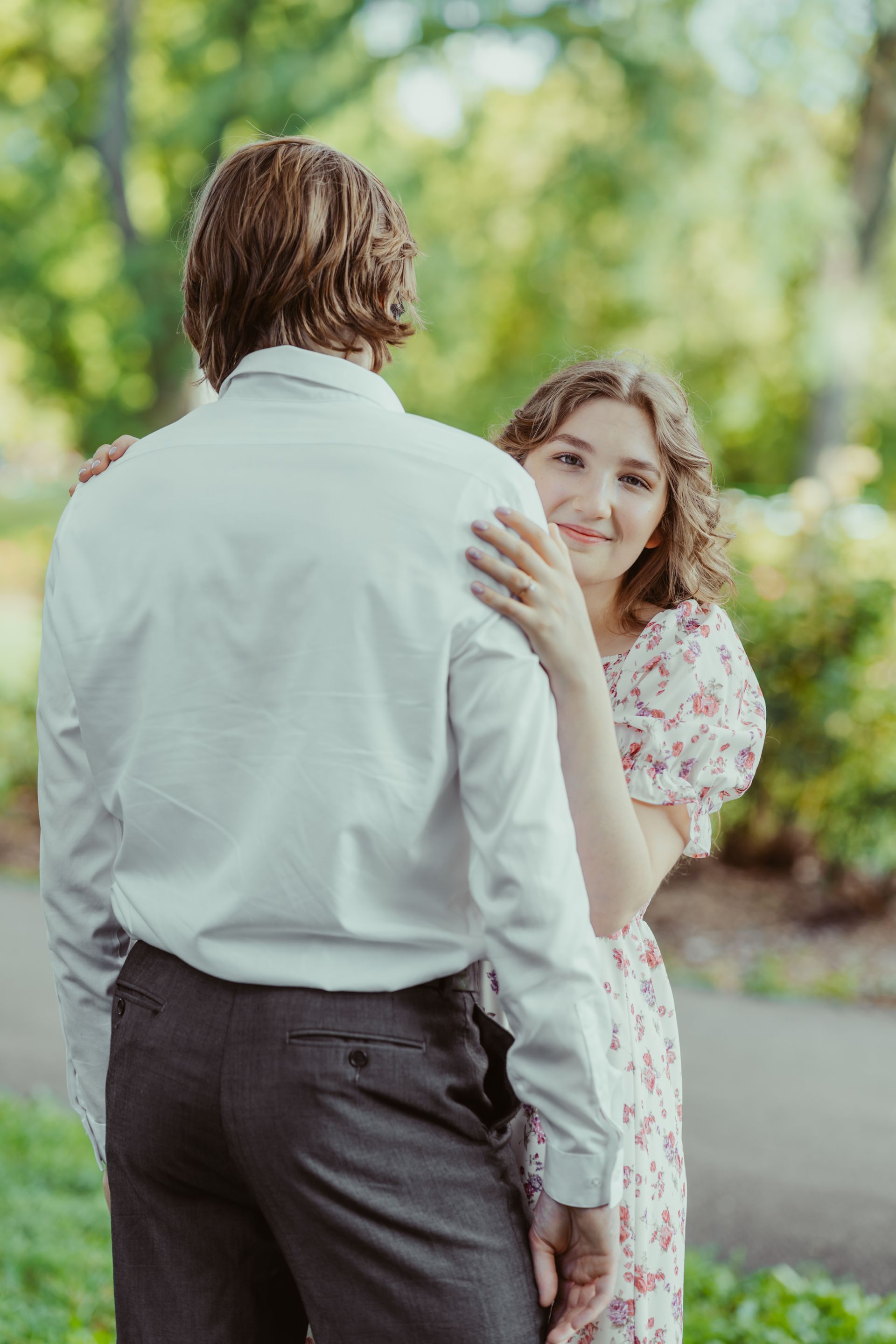 A man and a woman are standing next to each other in a park.