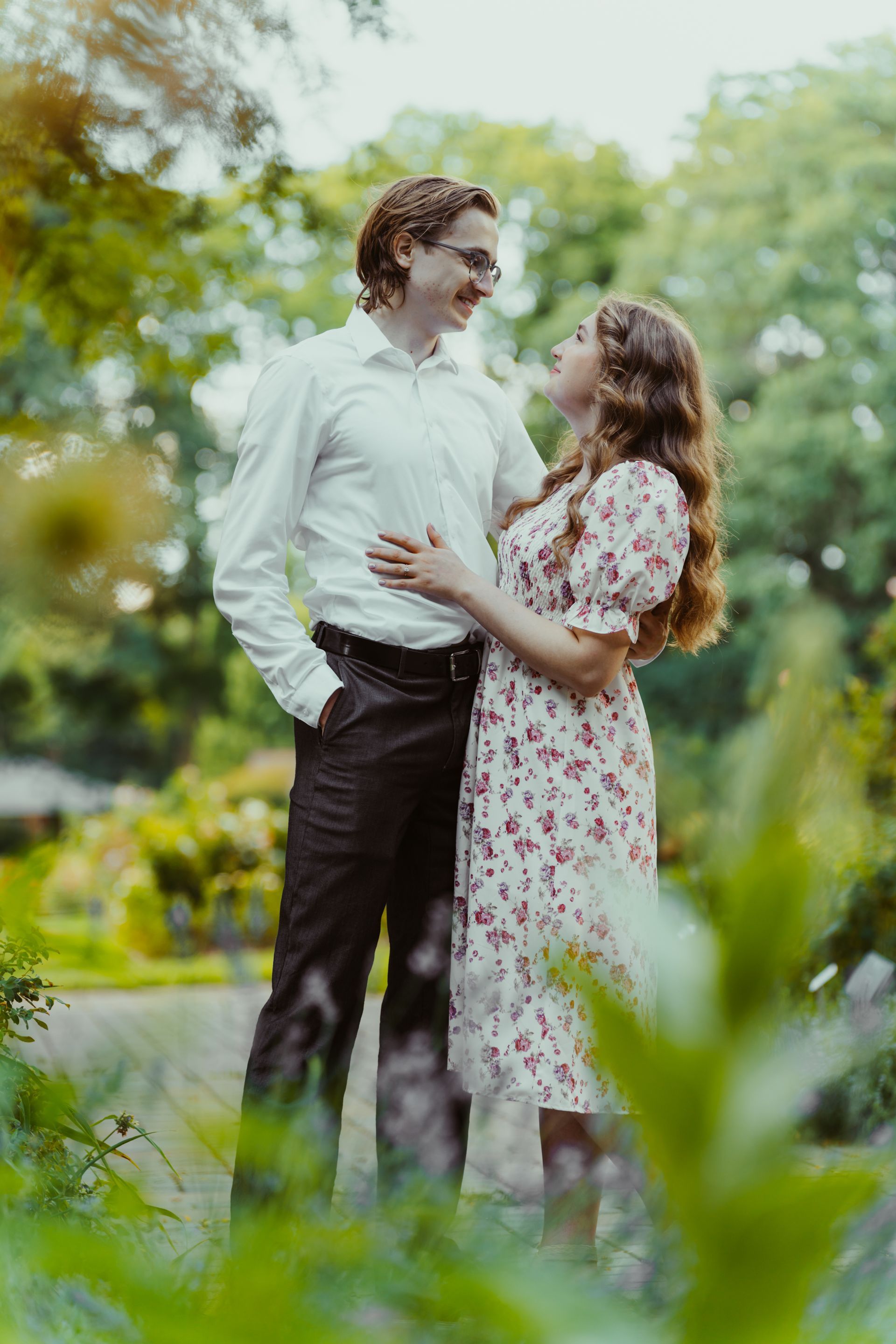 A man and a woman are standing next to each other in a park.