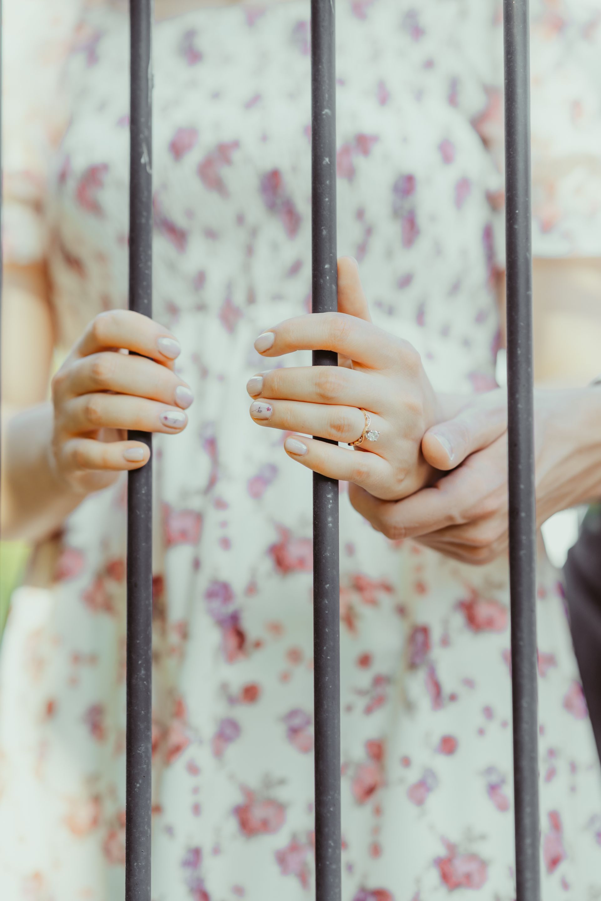 A man and a woman are holding hands behind bars.