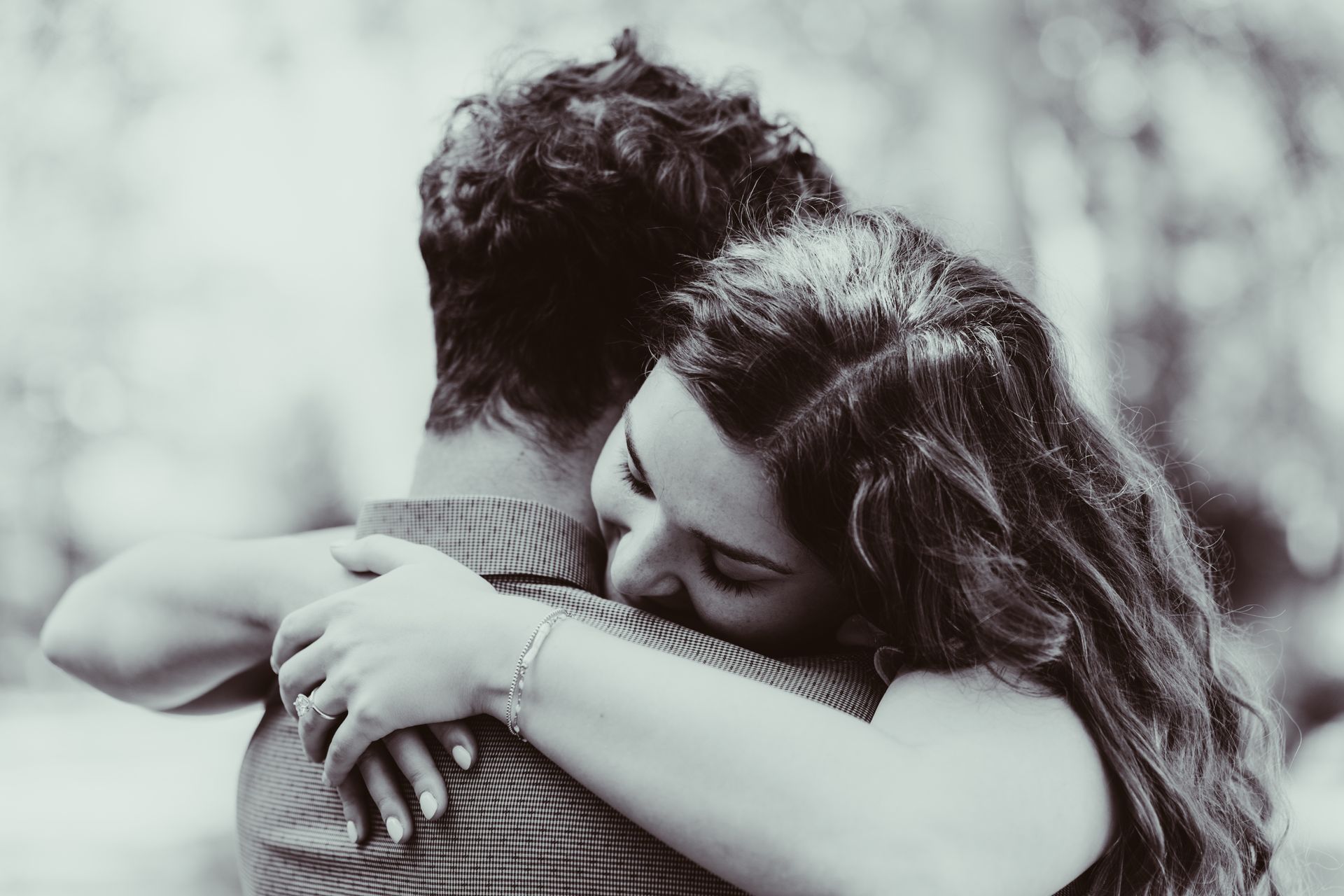 Woman embracing someone, face close to shoulder, black and white.