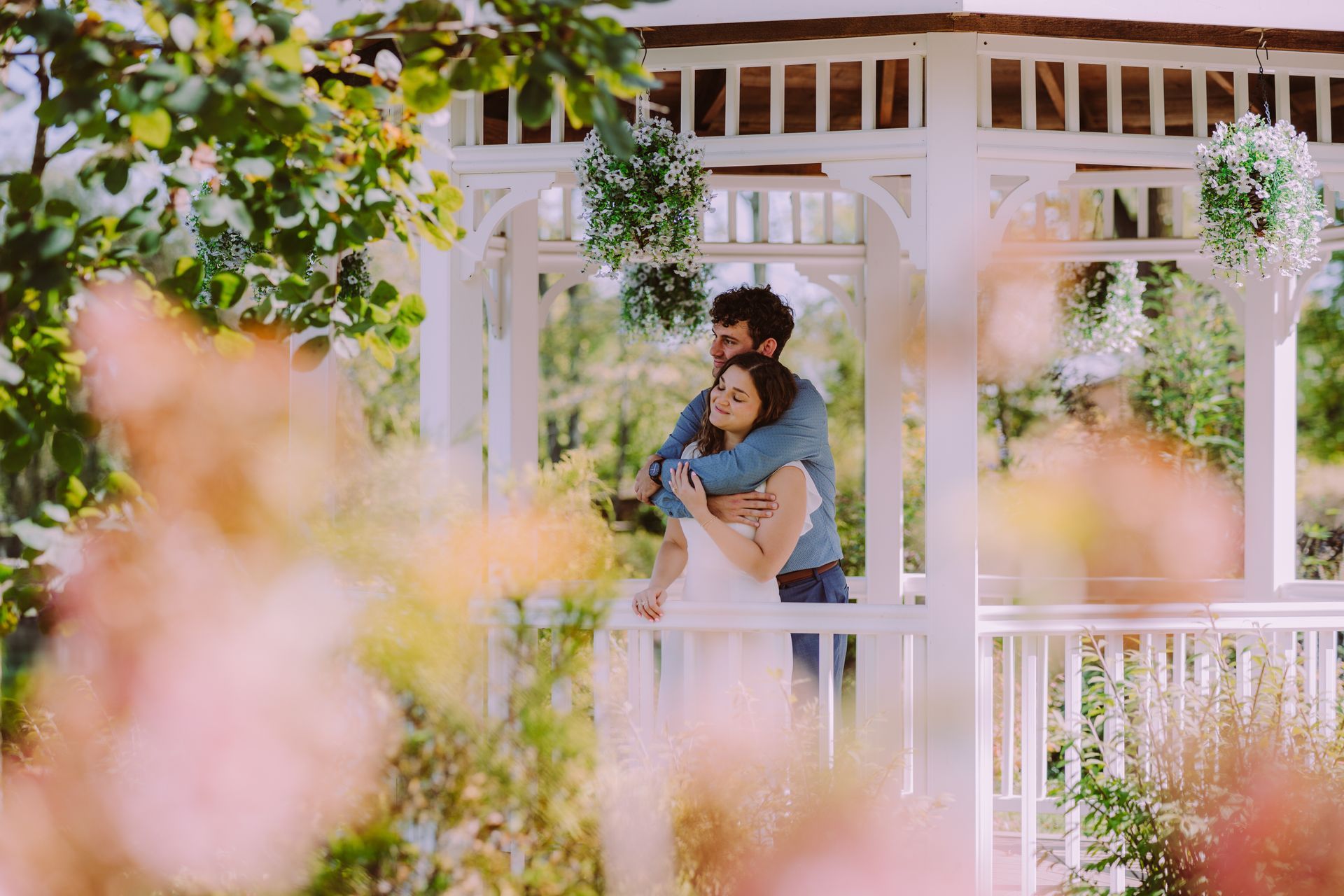 A man and a woman are kissing in front of the sun during engagement photo session in downtown columbus..