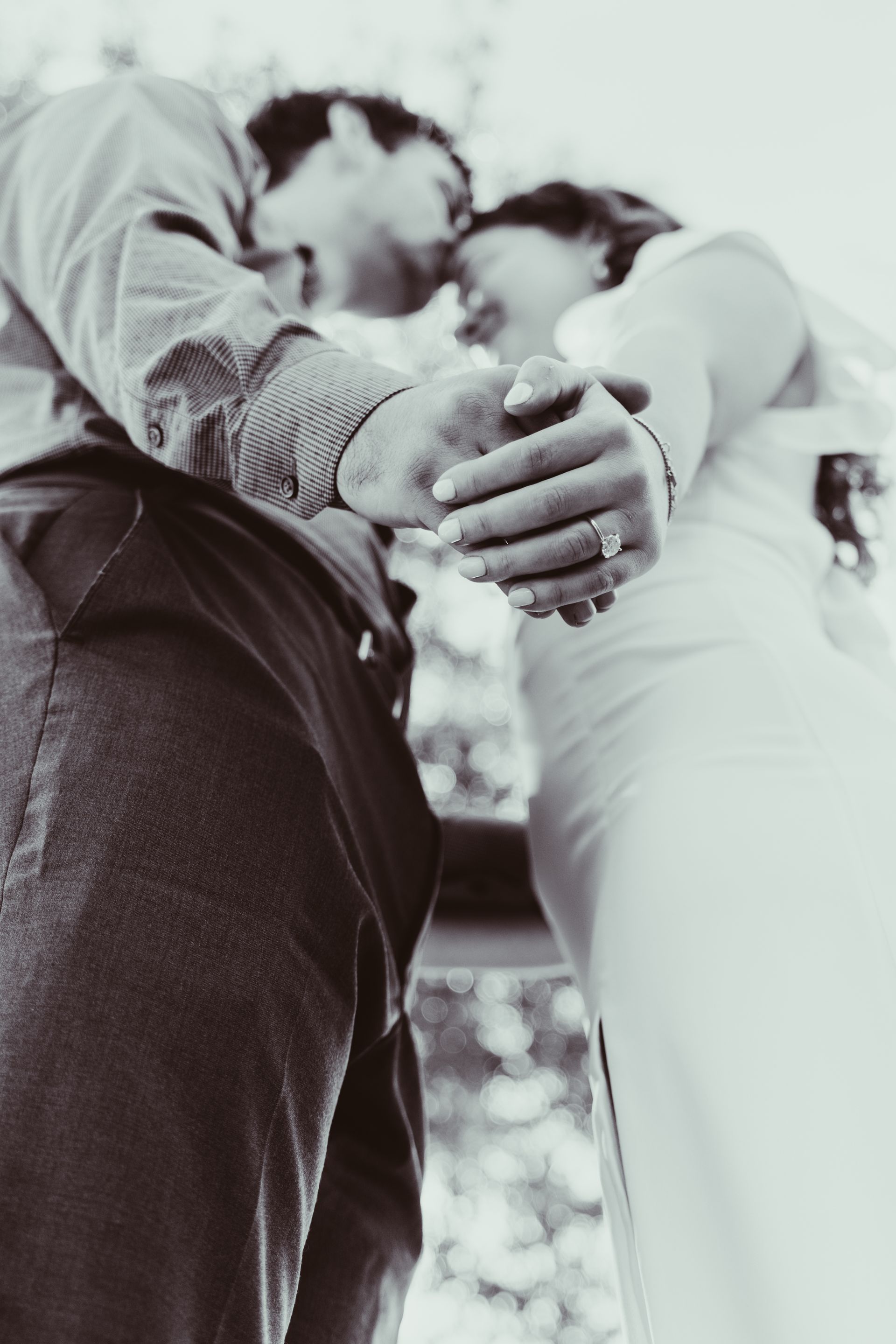 Couple holding hands, foreheads touching, close embrace, sepia toned, soft lighting.
