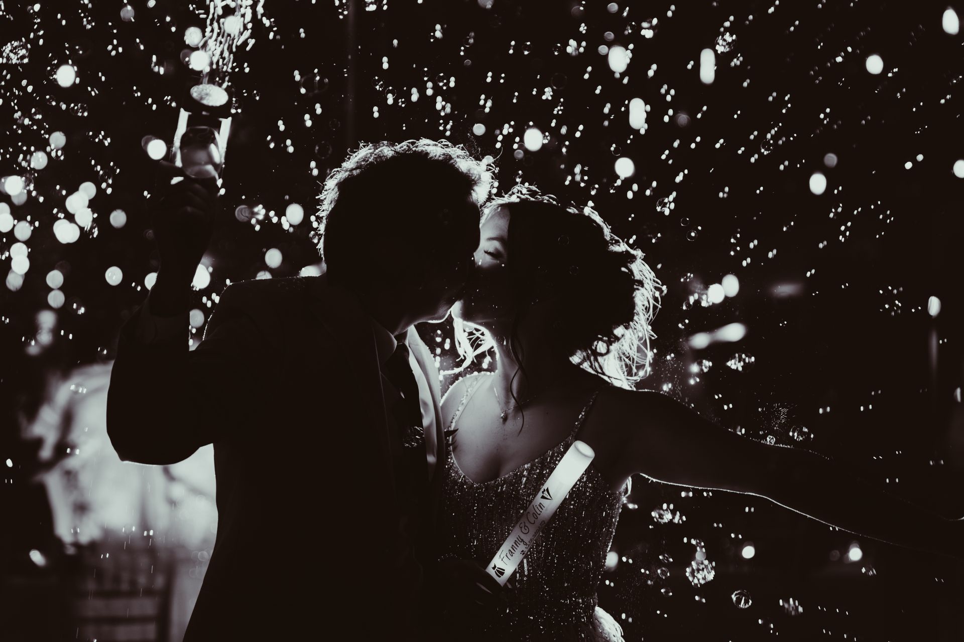 Couple kissing in the rain, silhouette, confetti, black and white, night, celebration.