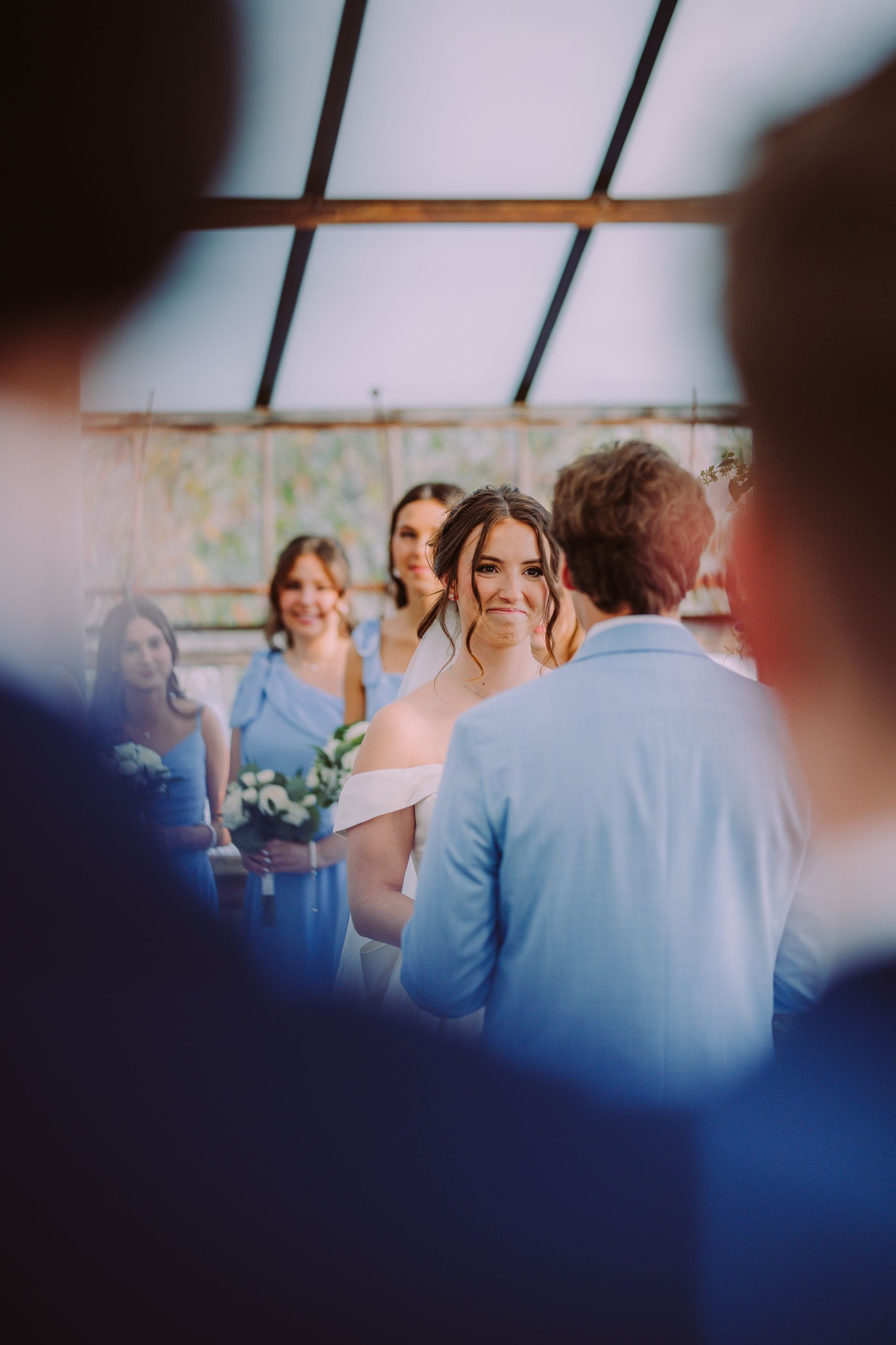 Bride and groom at outdoor ceremony; bridesmaids in blue dresses; smiling faces.