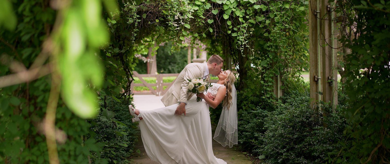 a bride and groom are kissing under an archway in a garden at franklin park conservatory.