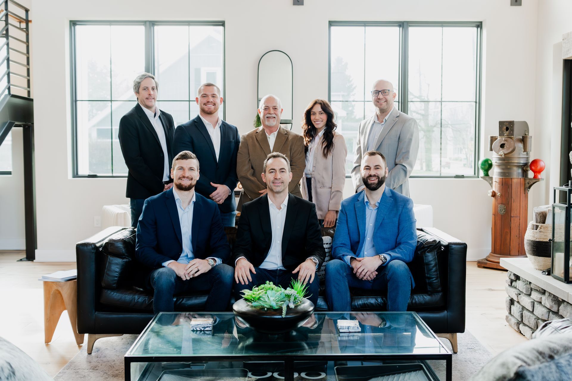Group of people posing for a photo in a modern office, sitting and standing, wearing business attire.  | Photos by Kodjoarts