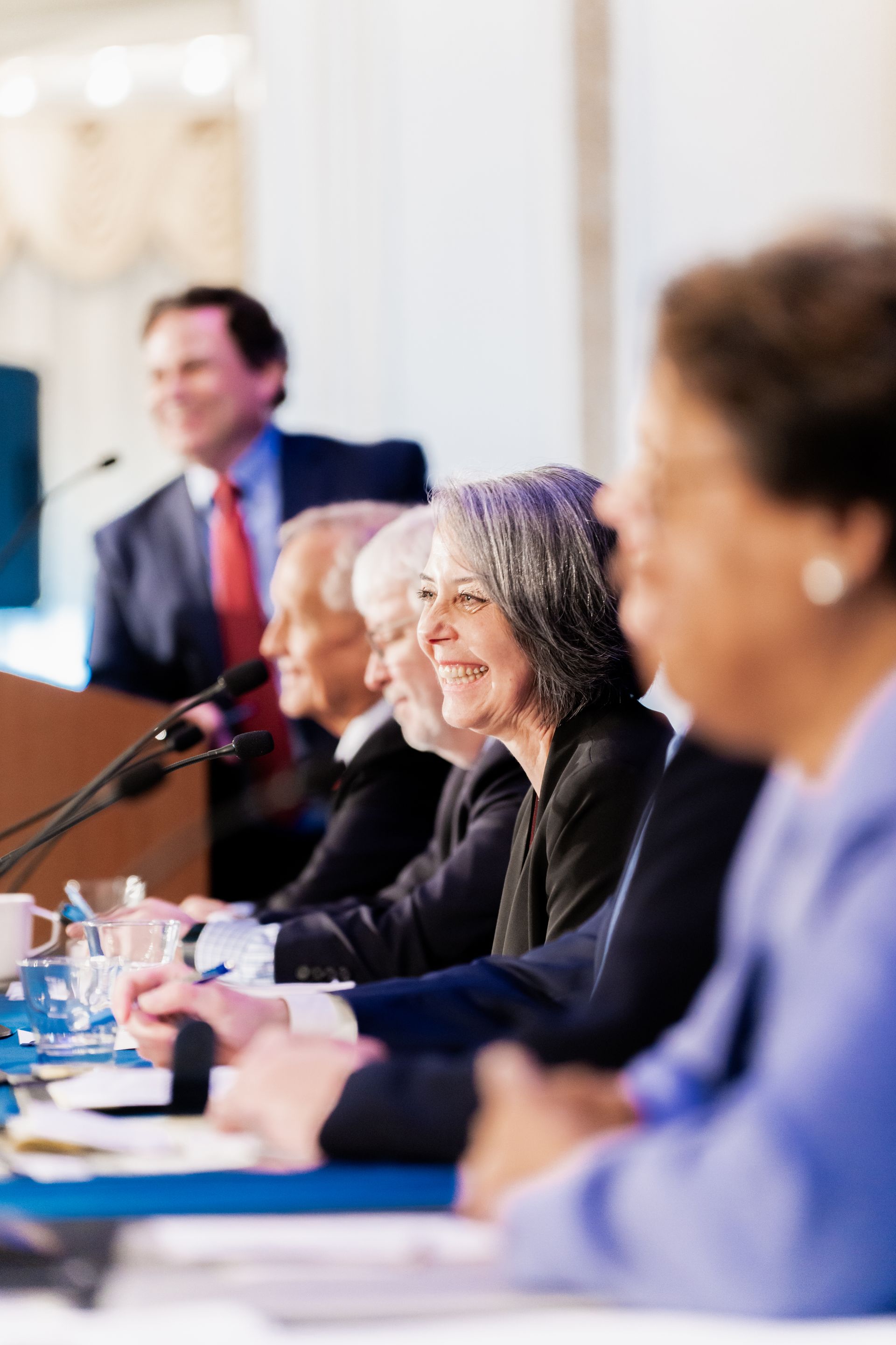 A group of people are sitting at a table in front of microphones