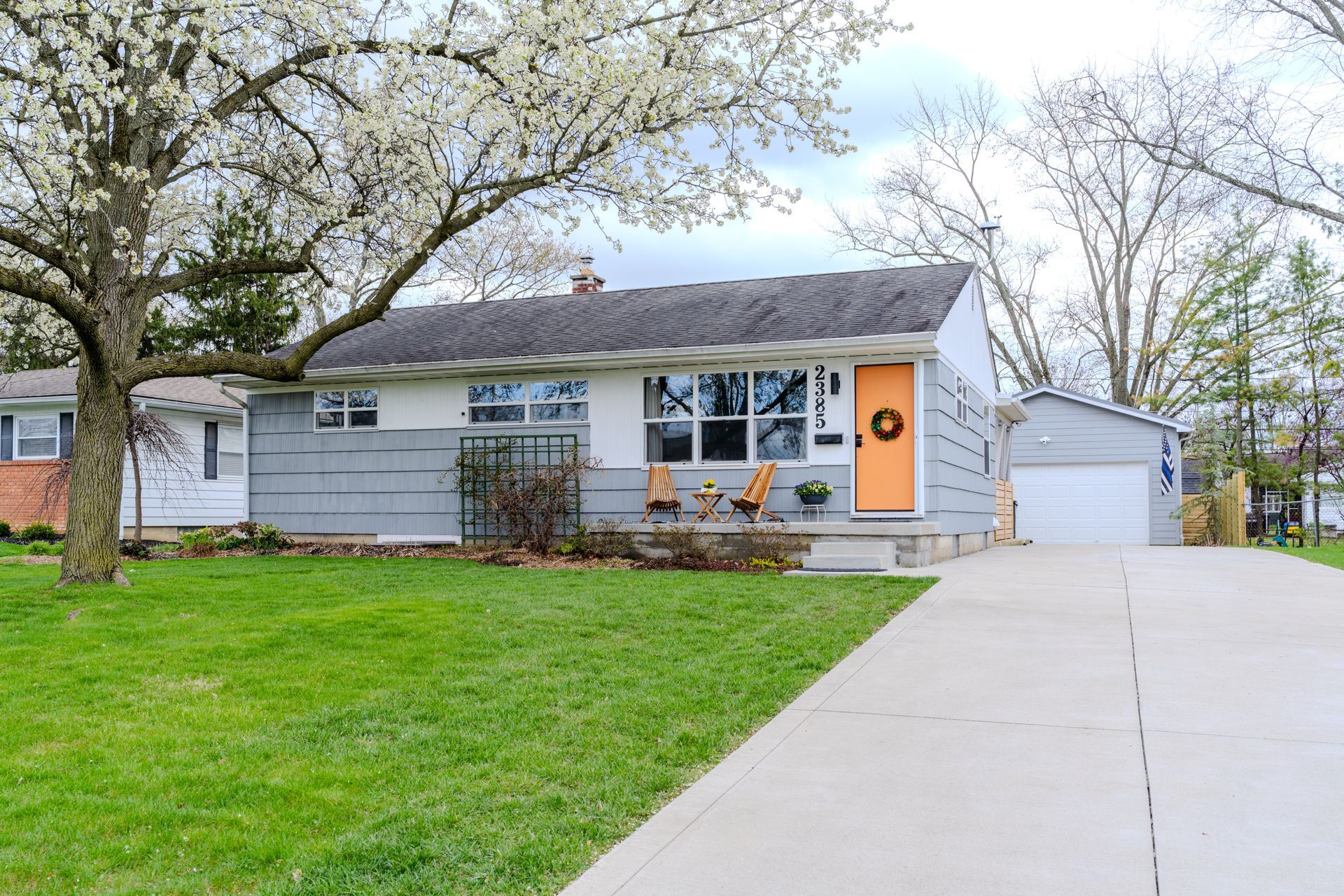 A house with a large lawn and a driveway in front of it.