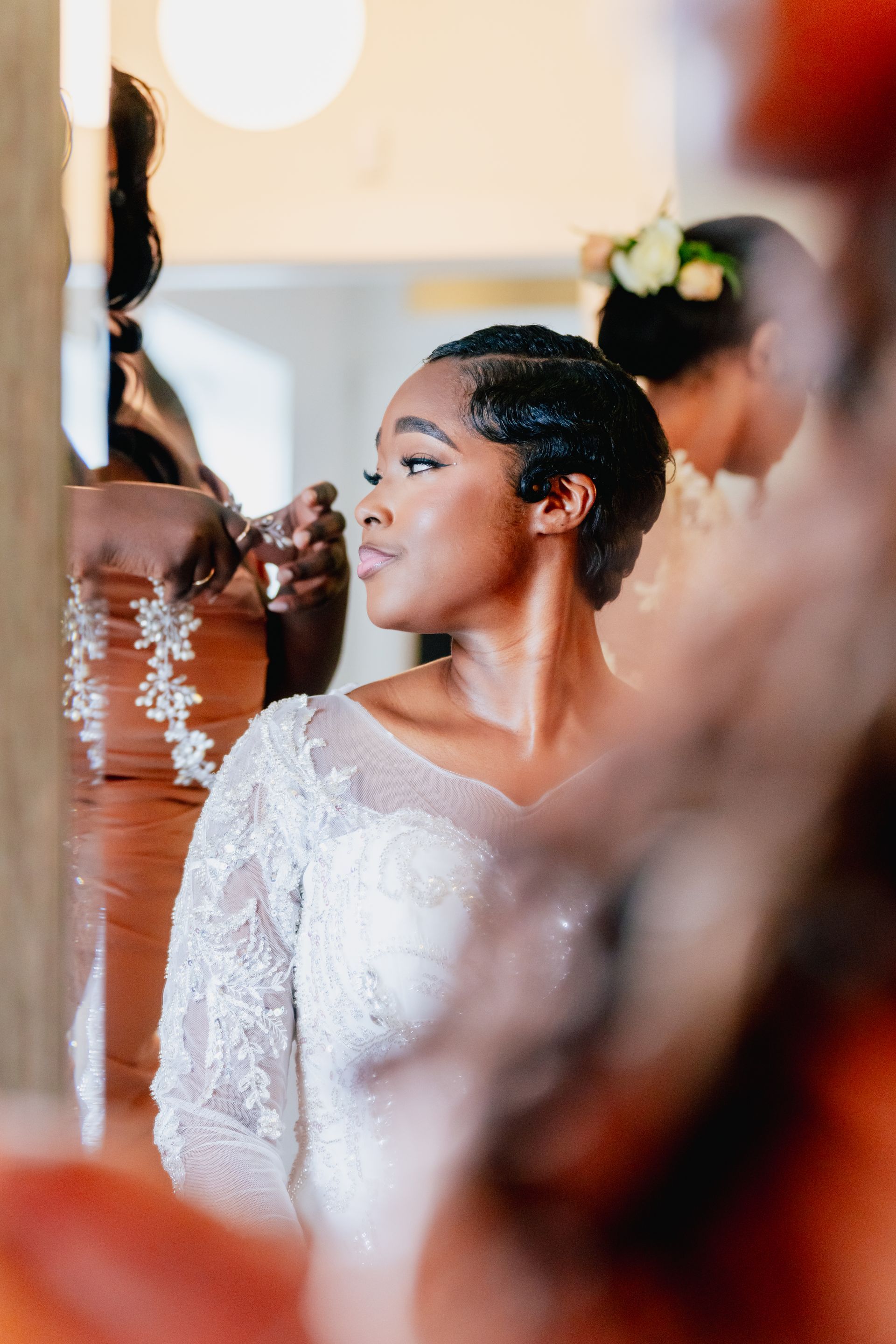 A bride is getting her hair done in front of a mirror.