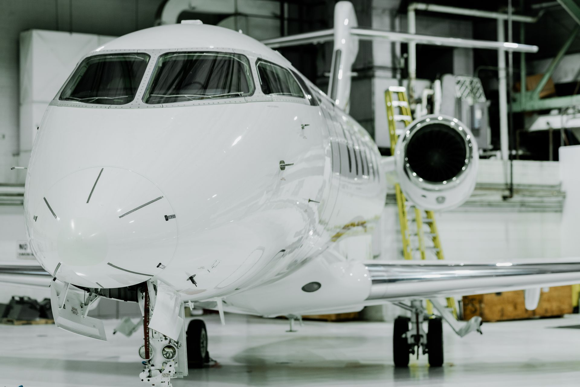 White private jet in a hangar, nose-on view, parked, waiting for takeoff.