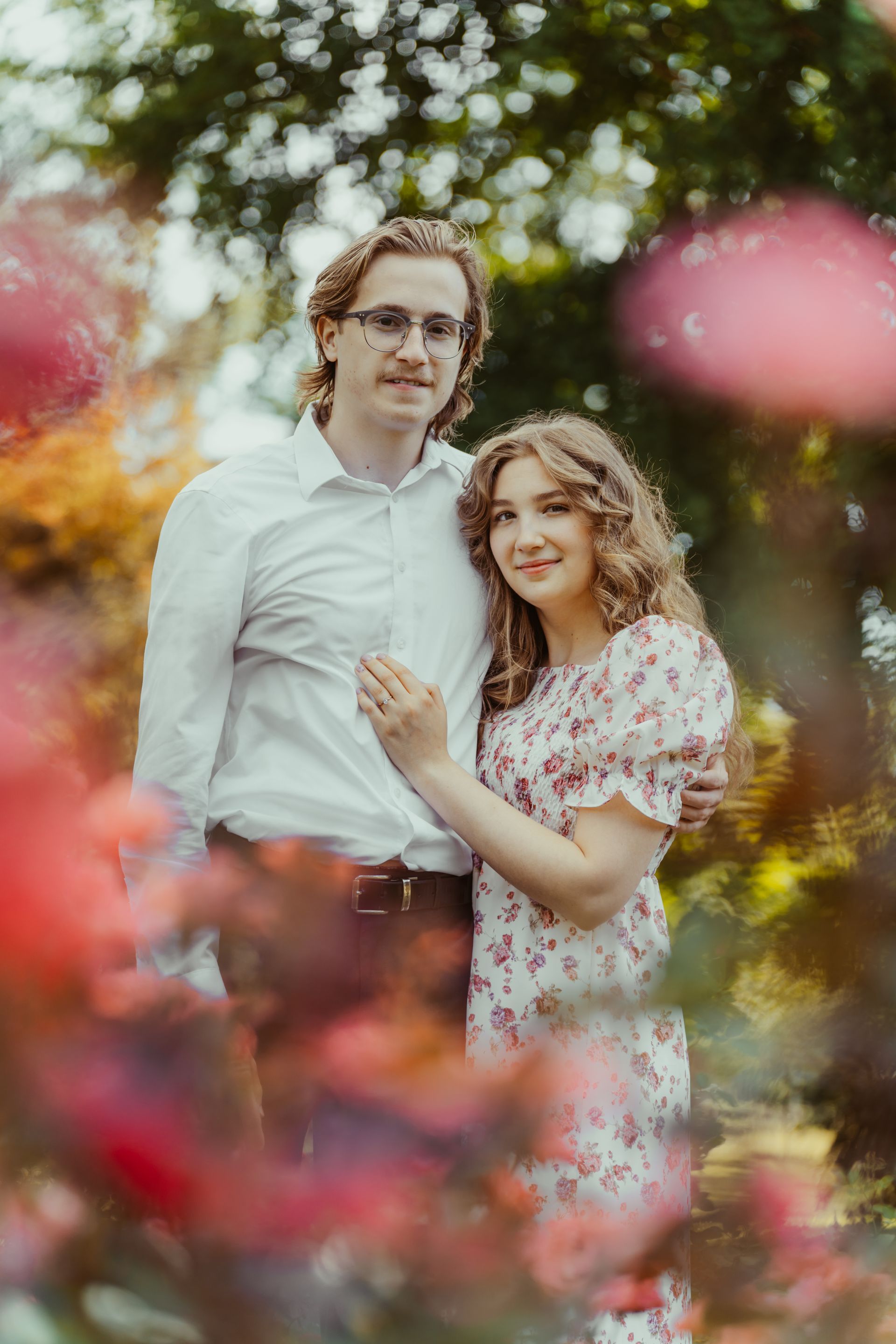 A man and a woman are standing next to each other in a field of flowers.