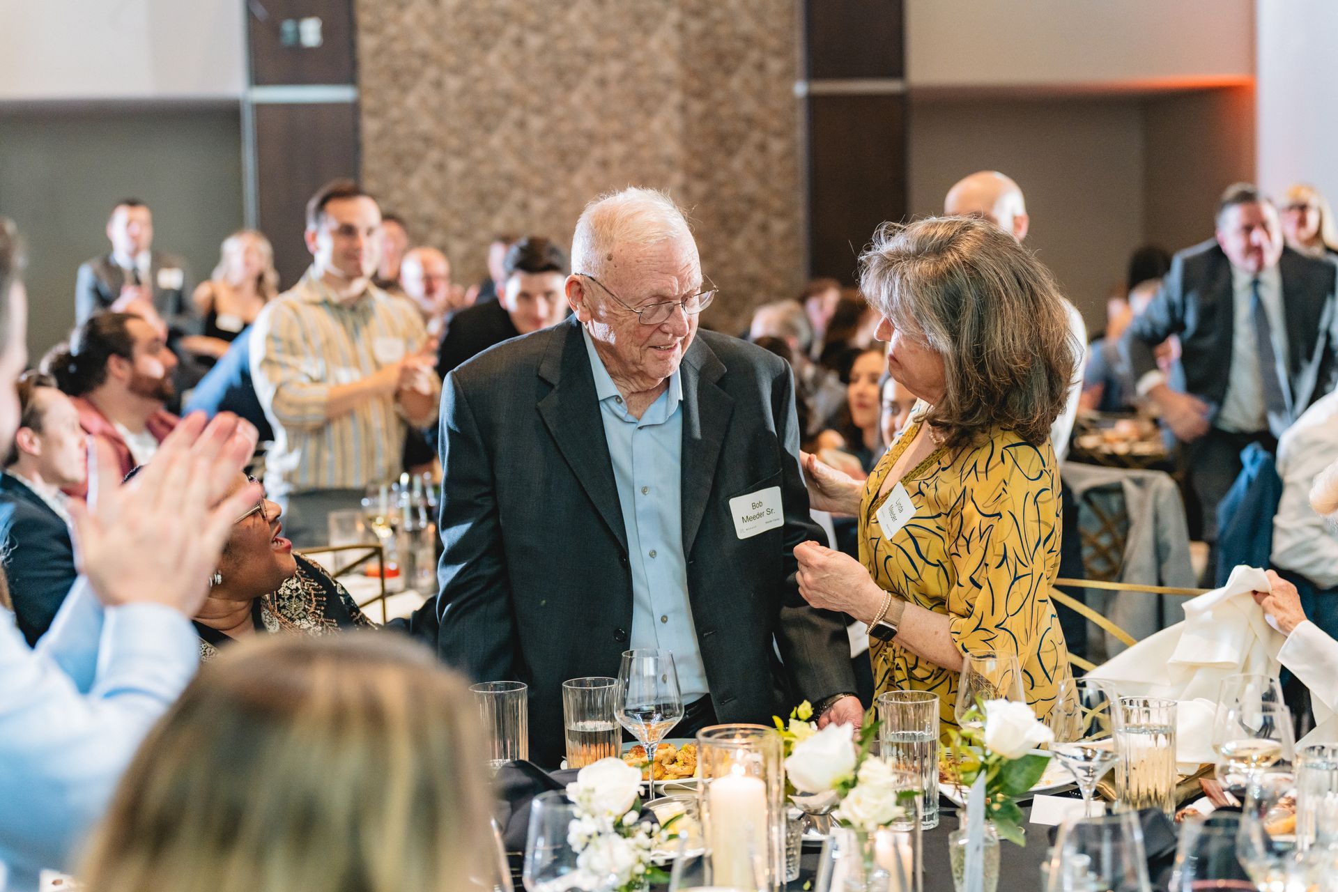 A man and a woman are standing next to each other at a table at a party.
