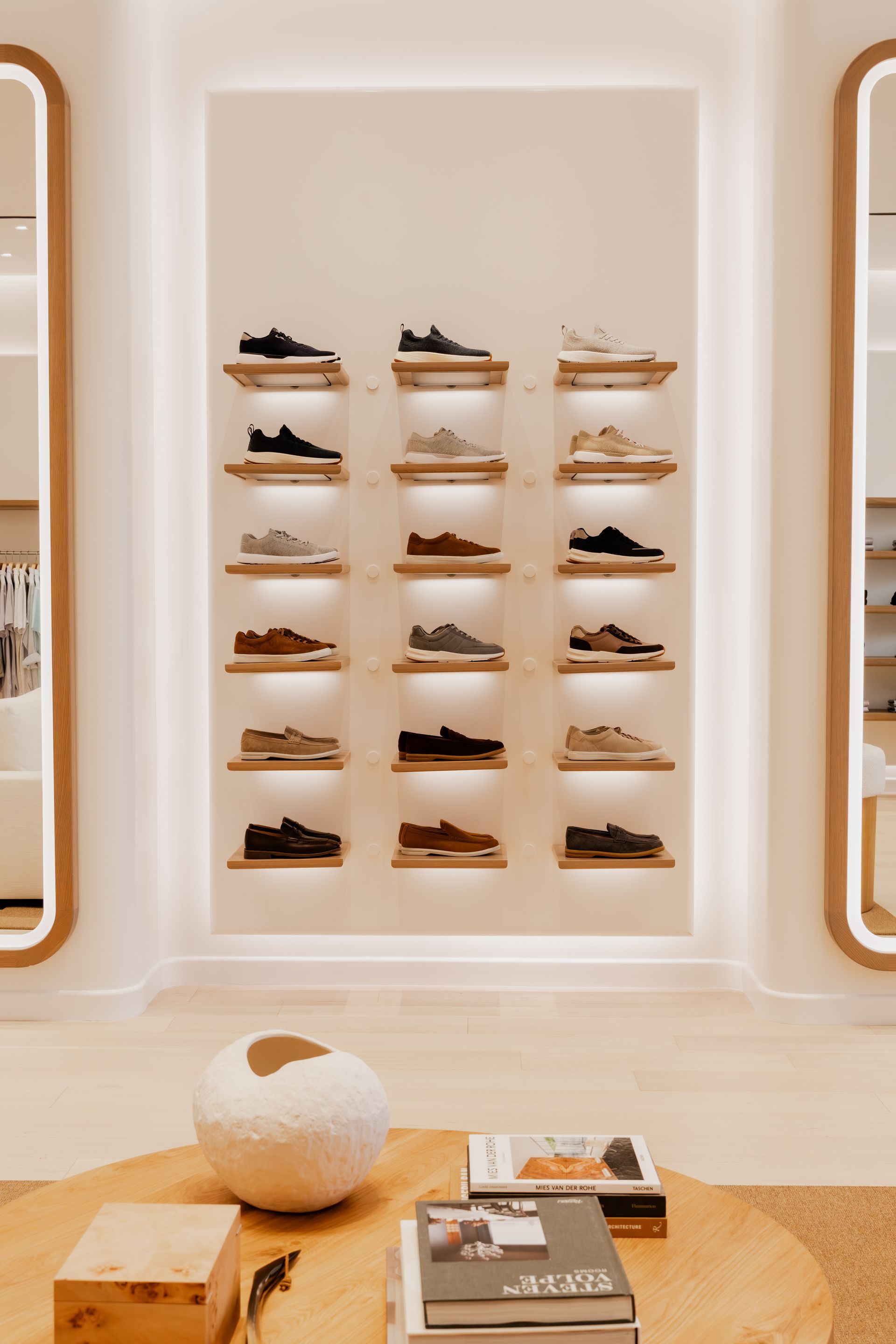 Sneaker display in a brightly lit store with shoes on wooden shelves. A low table is in the foreground.