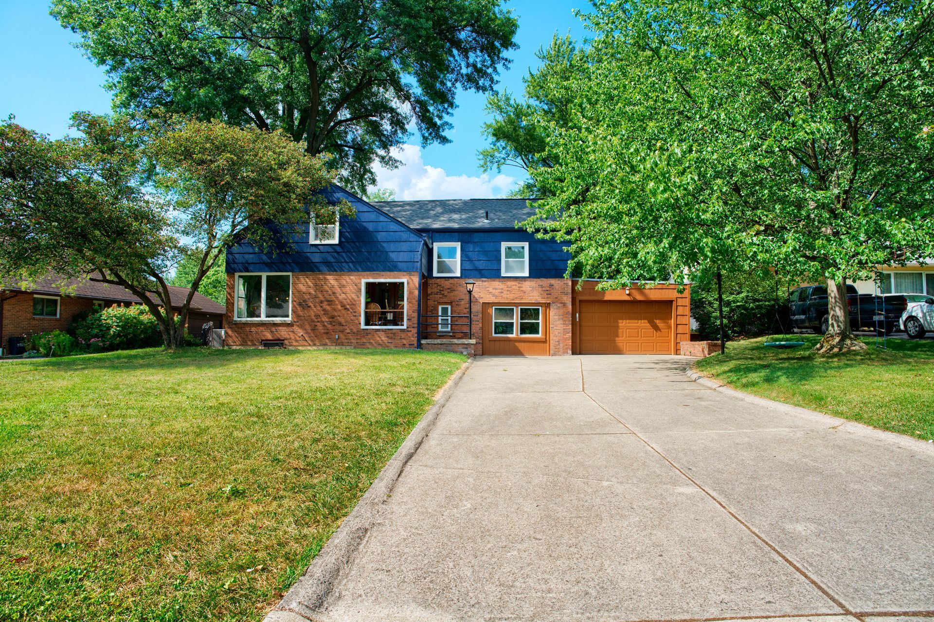 A brick house with a blue roof and a driveway leading to it.