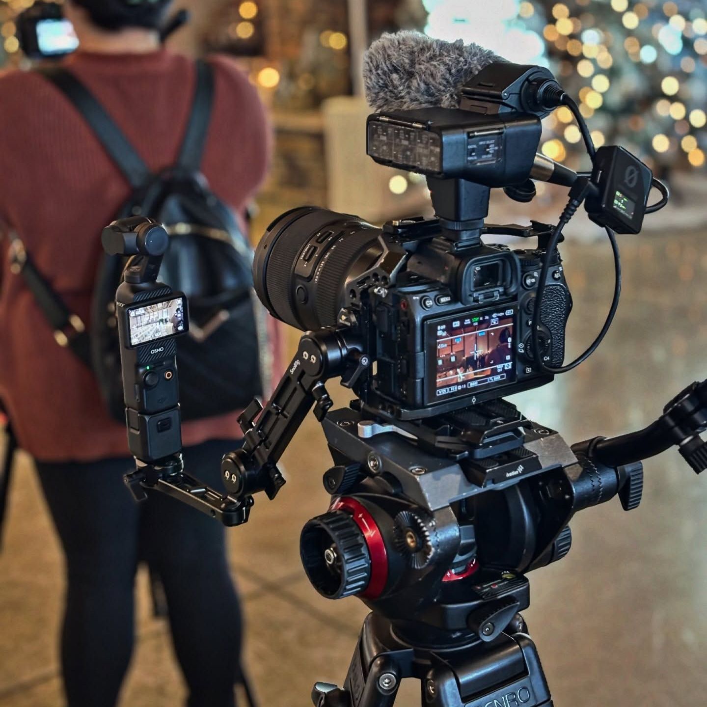 A person standing behind a camera that says ' nikon ' on it