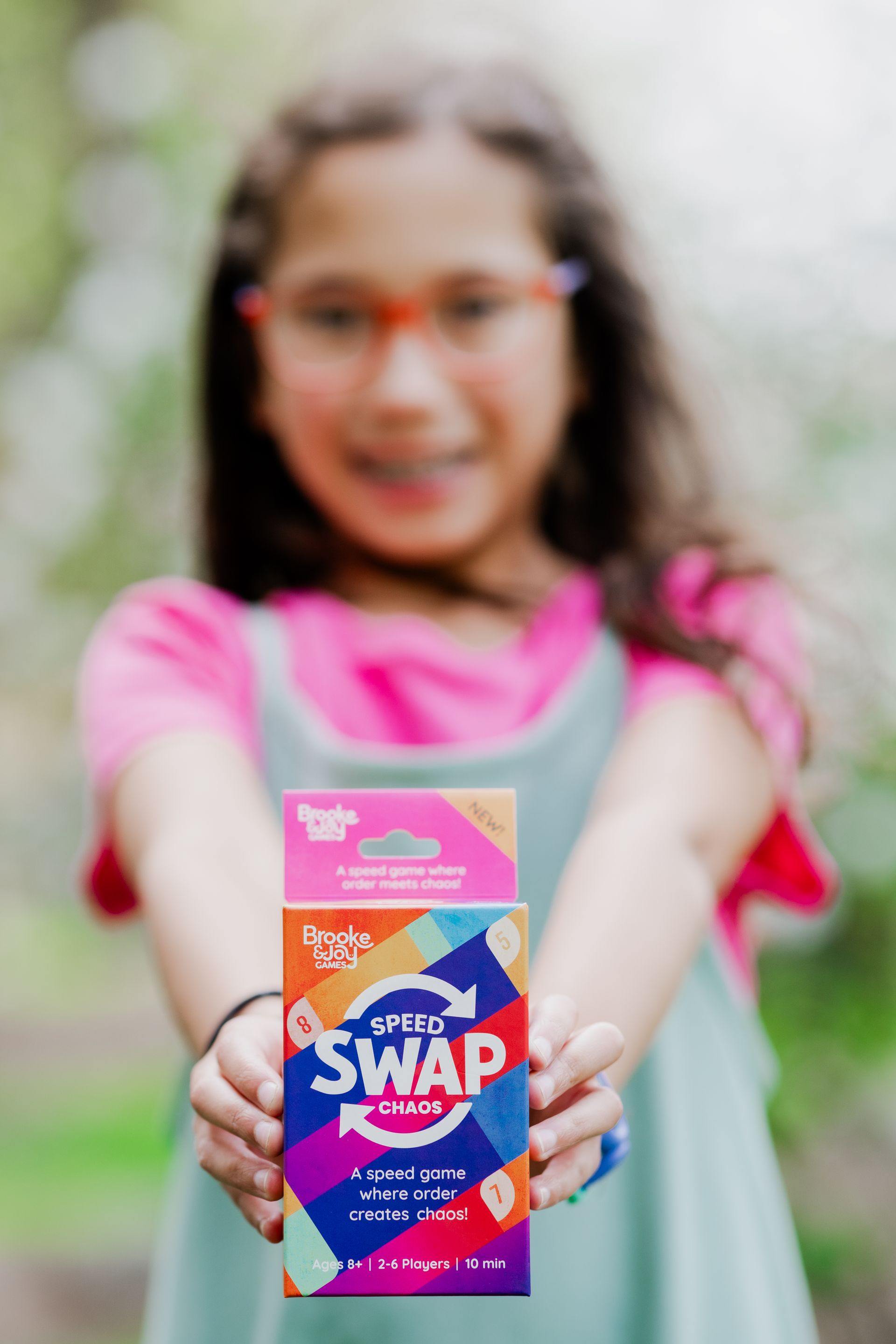 Child holding up a colorful “SWAP” snack box toward the camera outdoors