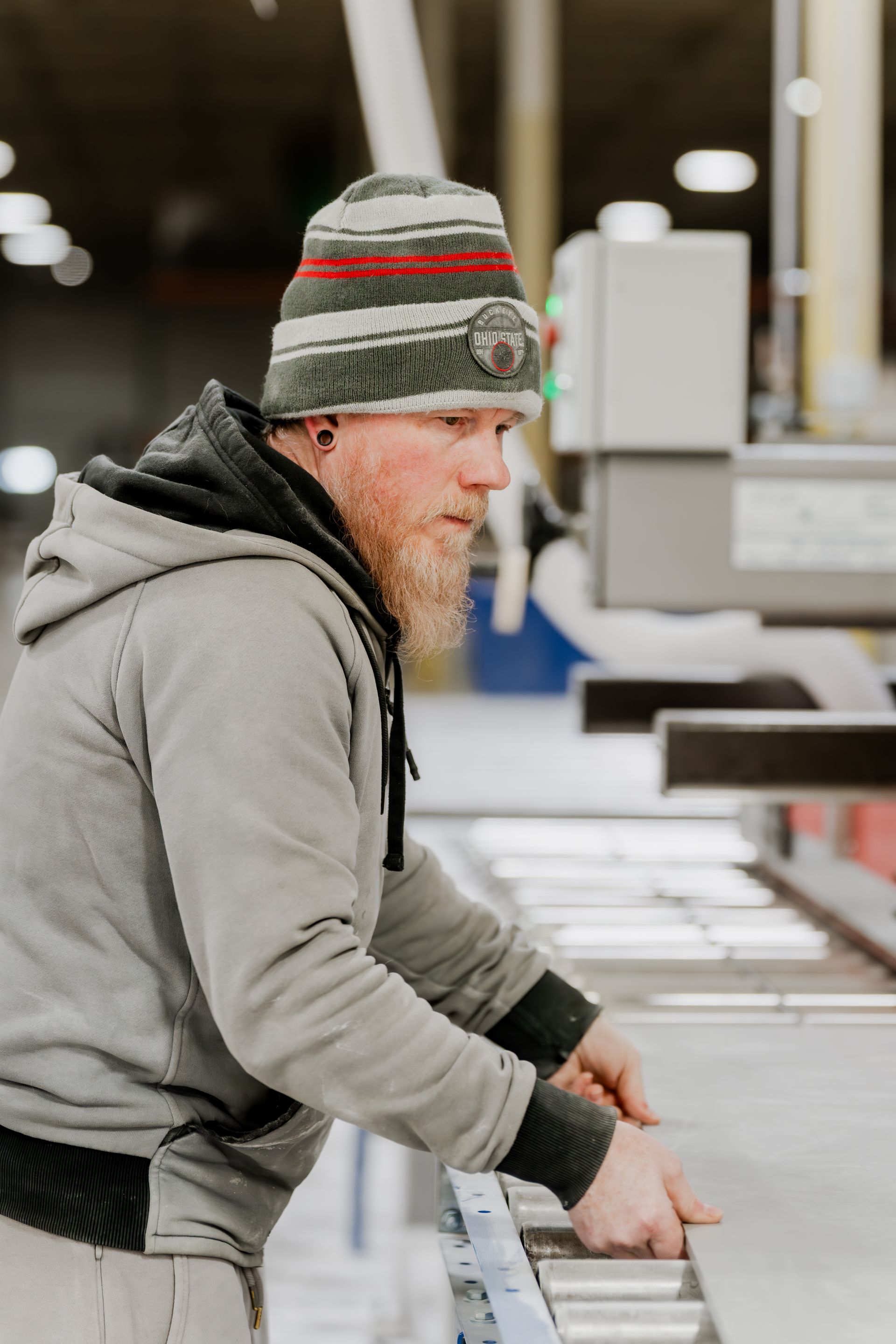 Man in beanie and hoodie working with machinery.