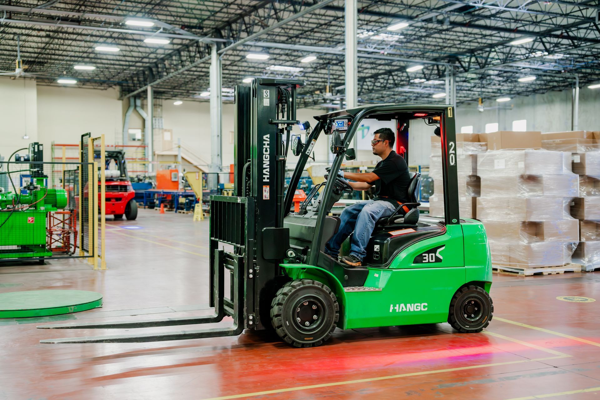 Forklift operator in a warehouse. Green forklift, man driving.
