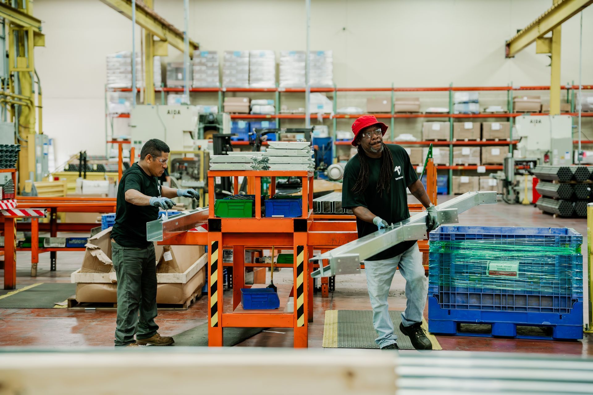 Two men are working on a piece of metal in a factory.