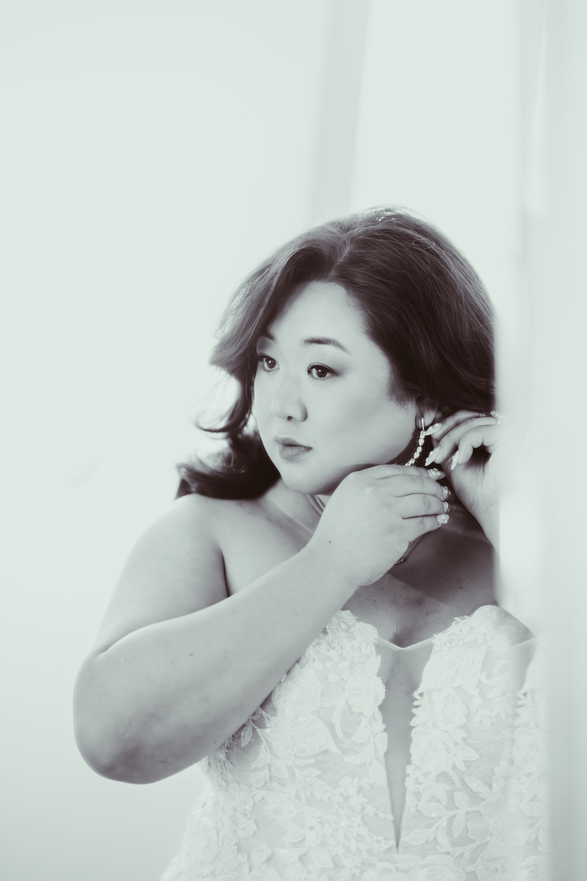 Woman in white strapless dress putting on earrings, looking down. Photo by Kodjo somana