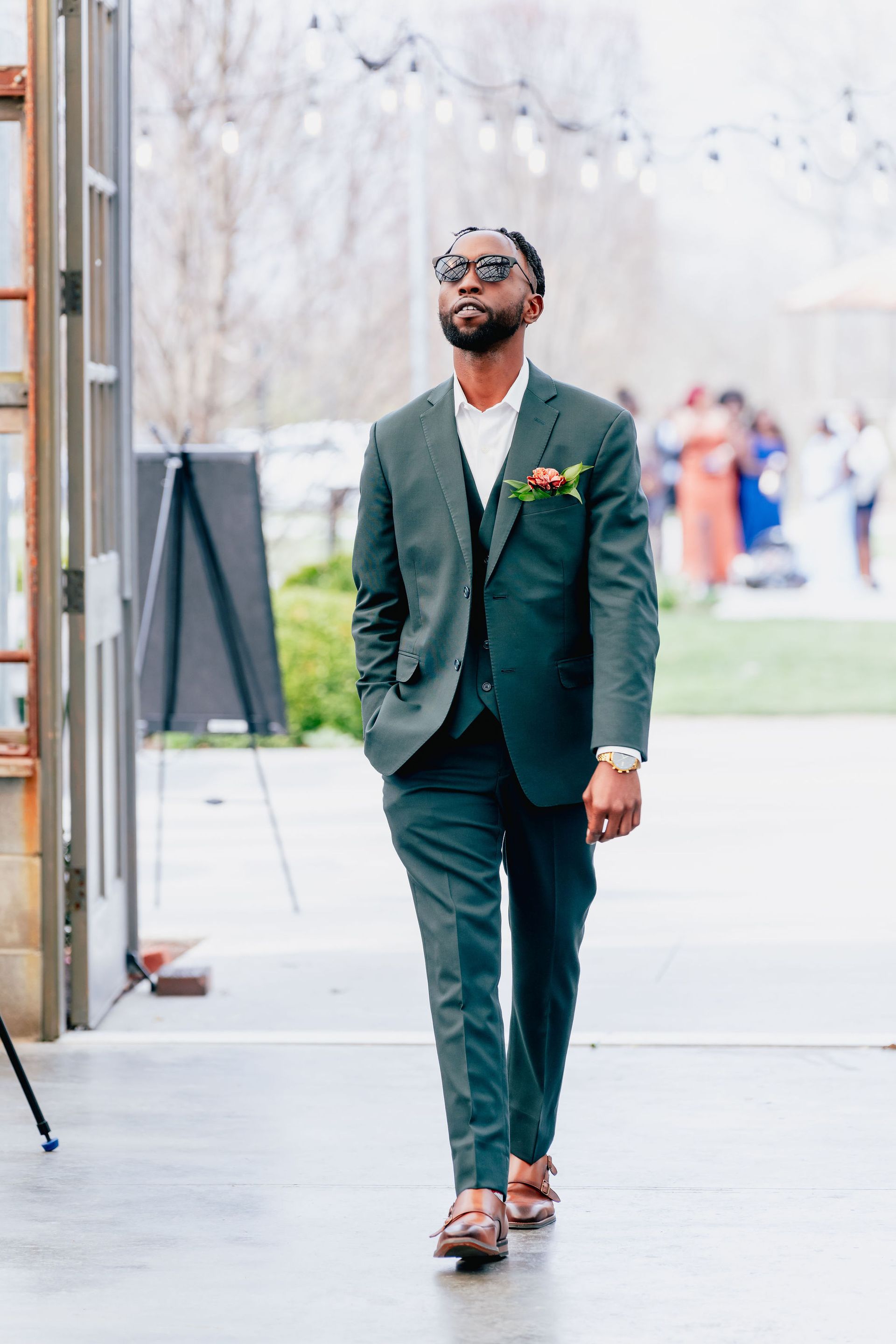 A man in a suit and sunglasses is walking down a sidewalk.