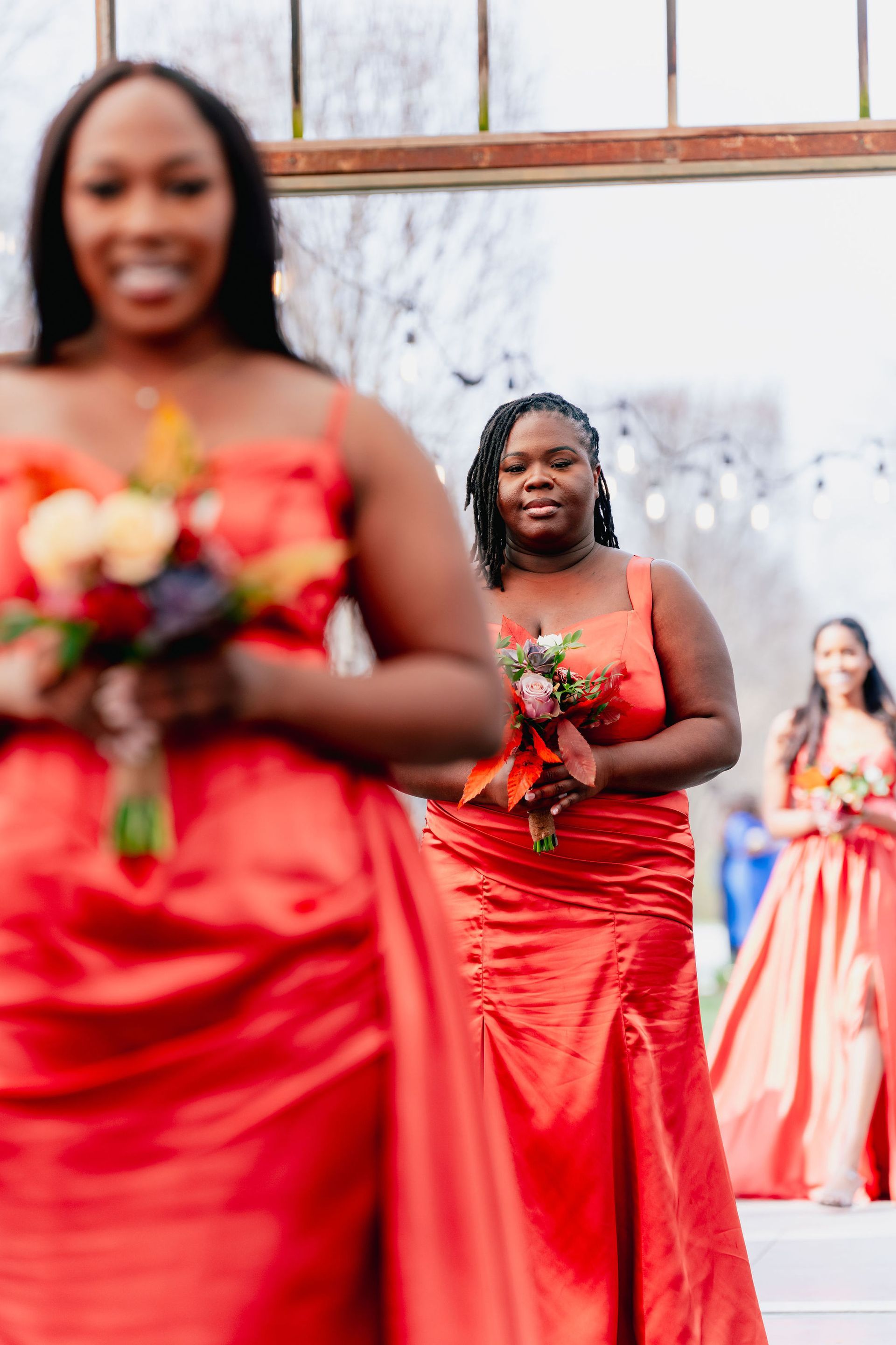 A group of bridesmaids in red dresses are walking down the aisle.