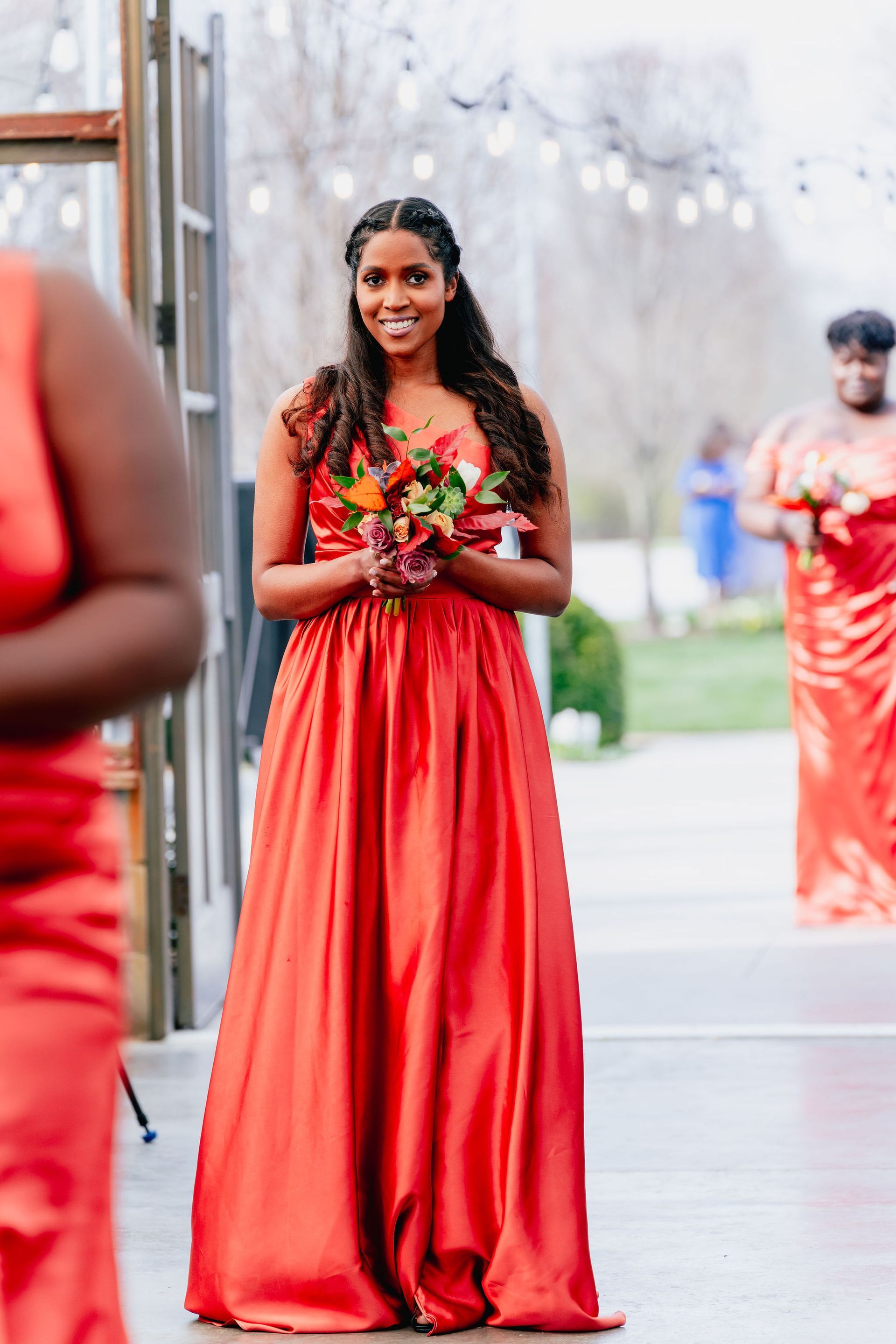 A woman in a red dress is holding a bouquet of flowers.