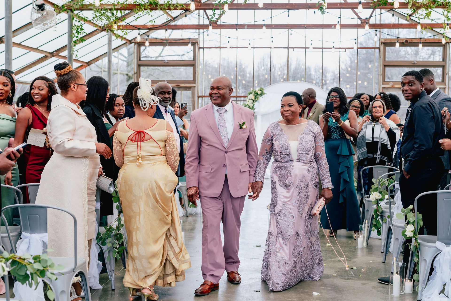 A bride and groom are walking down the aisle at their wedding in a greenhouse.