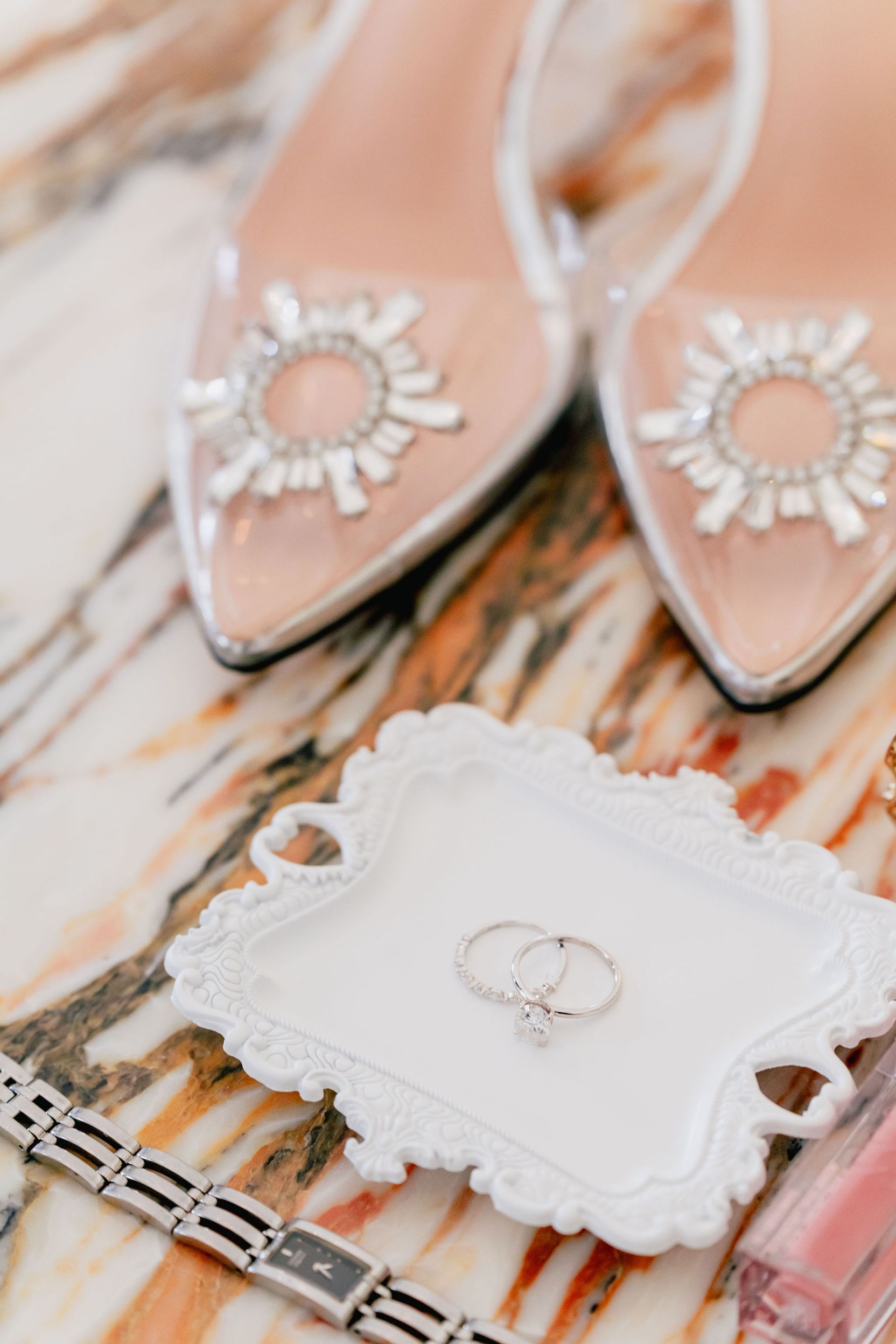 A pair of shoes , a bracelet , a ring and a tray are on a table.