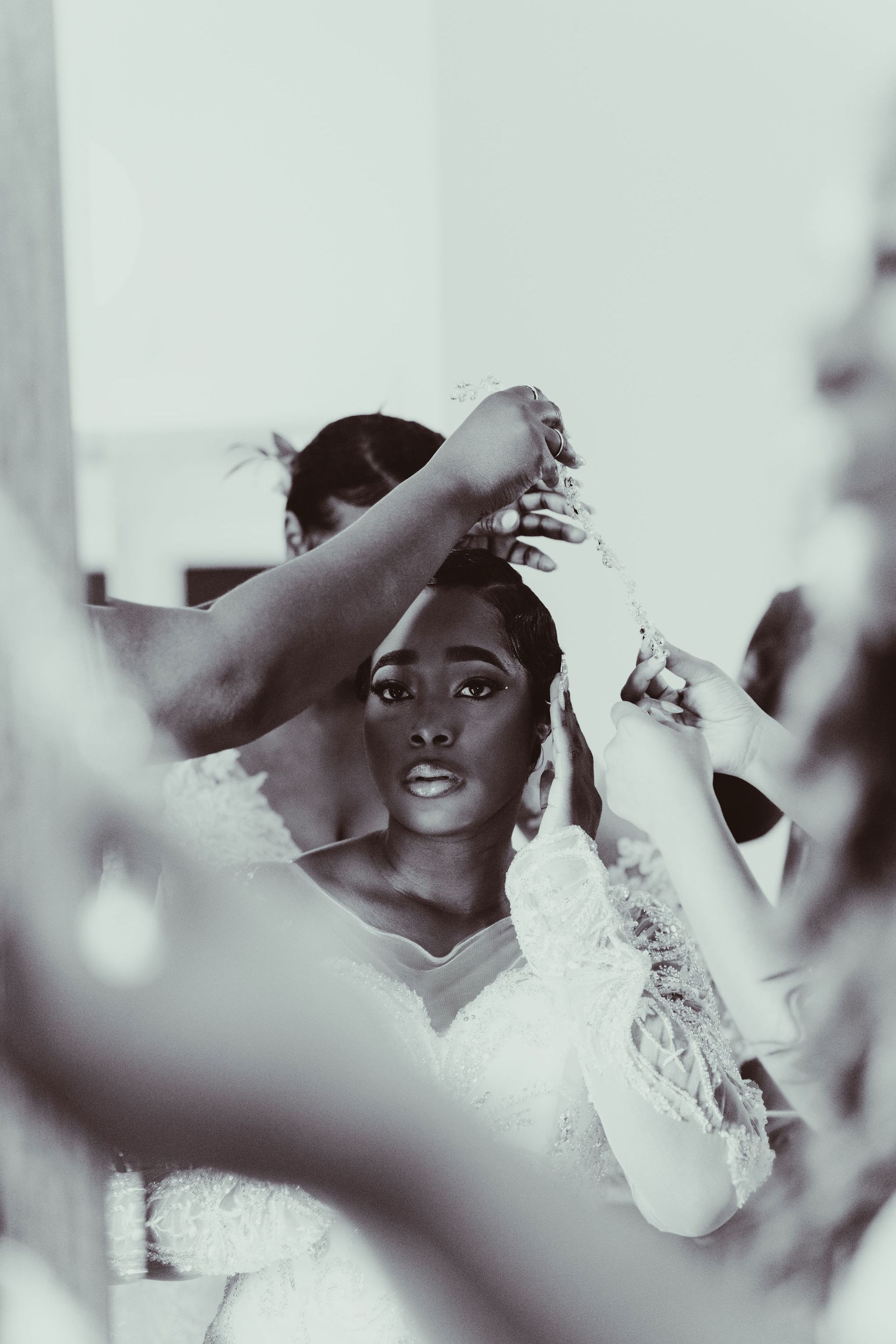 A woman in a wedding dress is getting her hair done in front of a mirror.