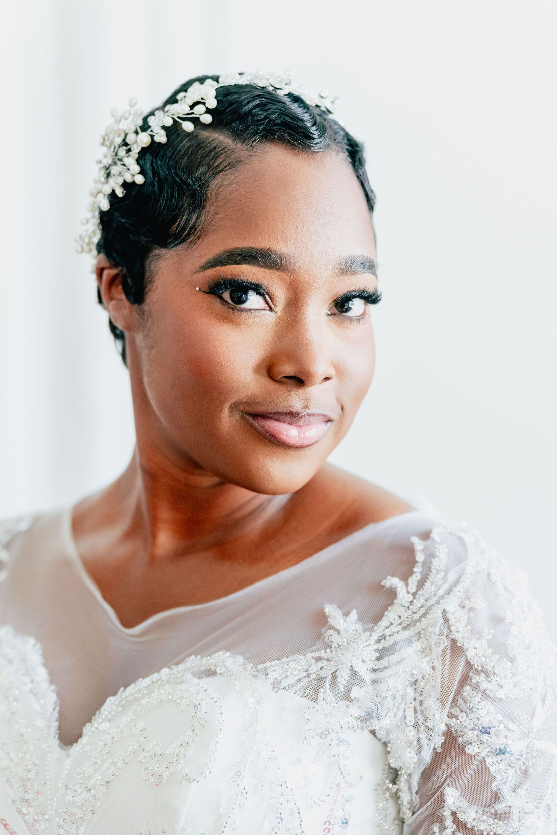 A close up of a woman wearing a wedding dress and a tiara.