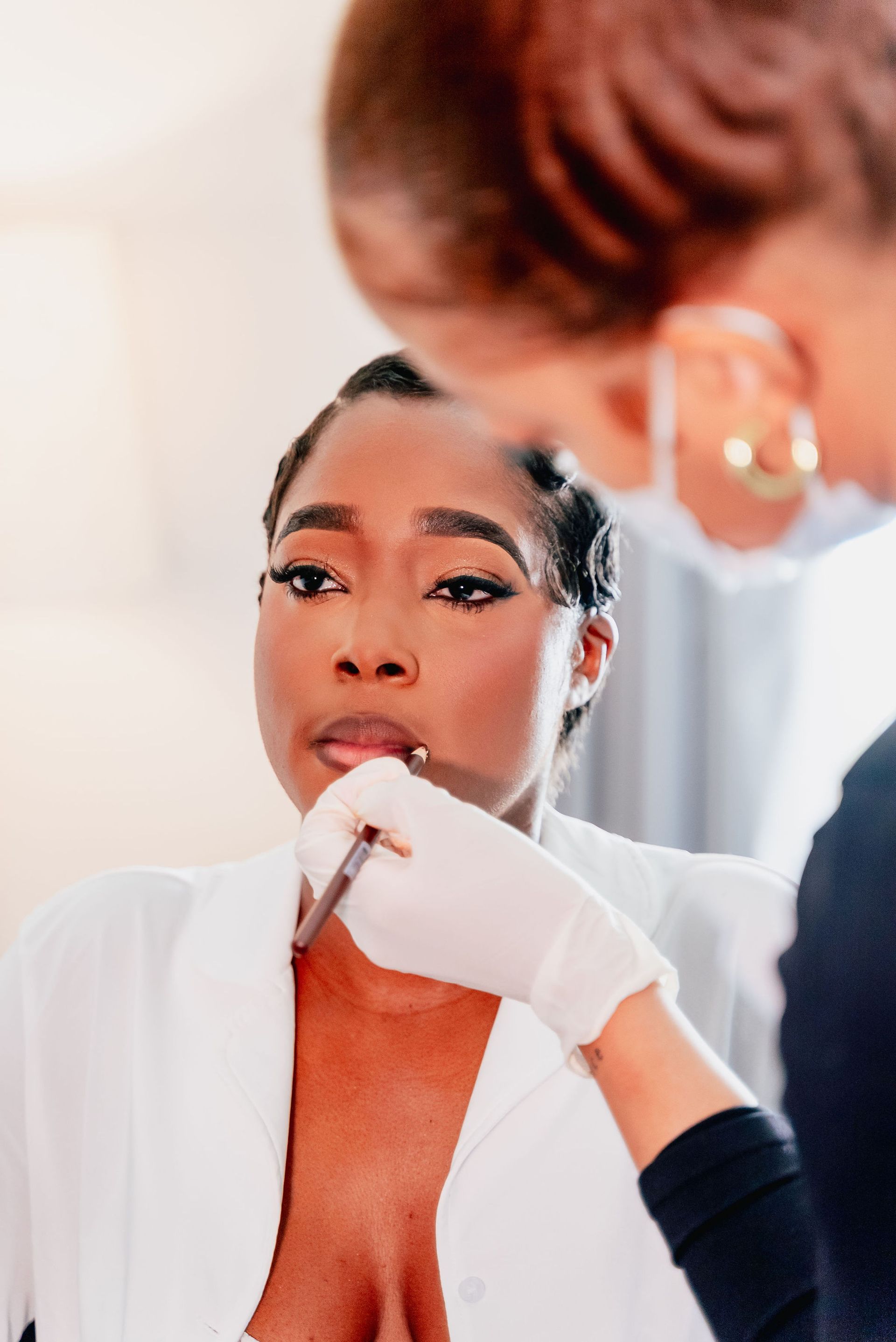 A woman is getting her makeup done in front of a mirror.