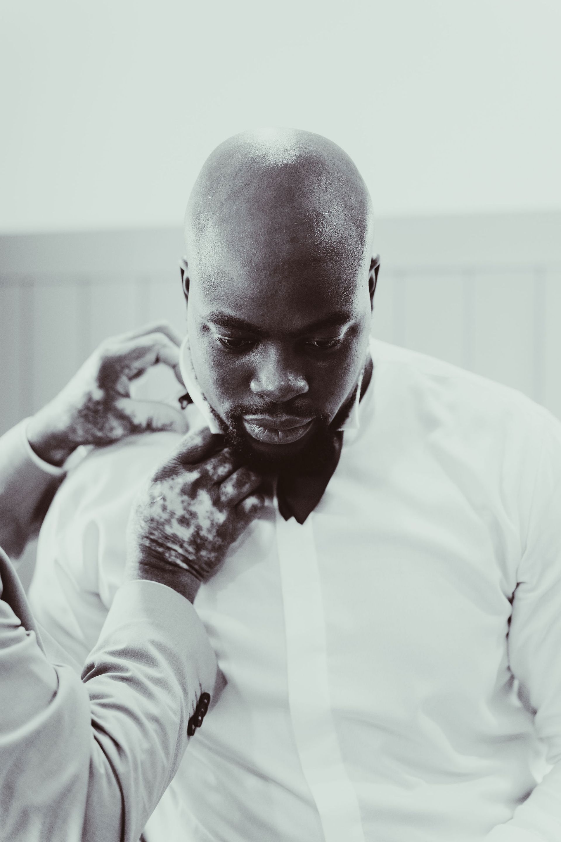 A black and white photo of a man getting ready for a wedding