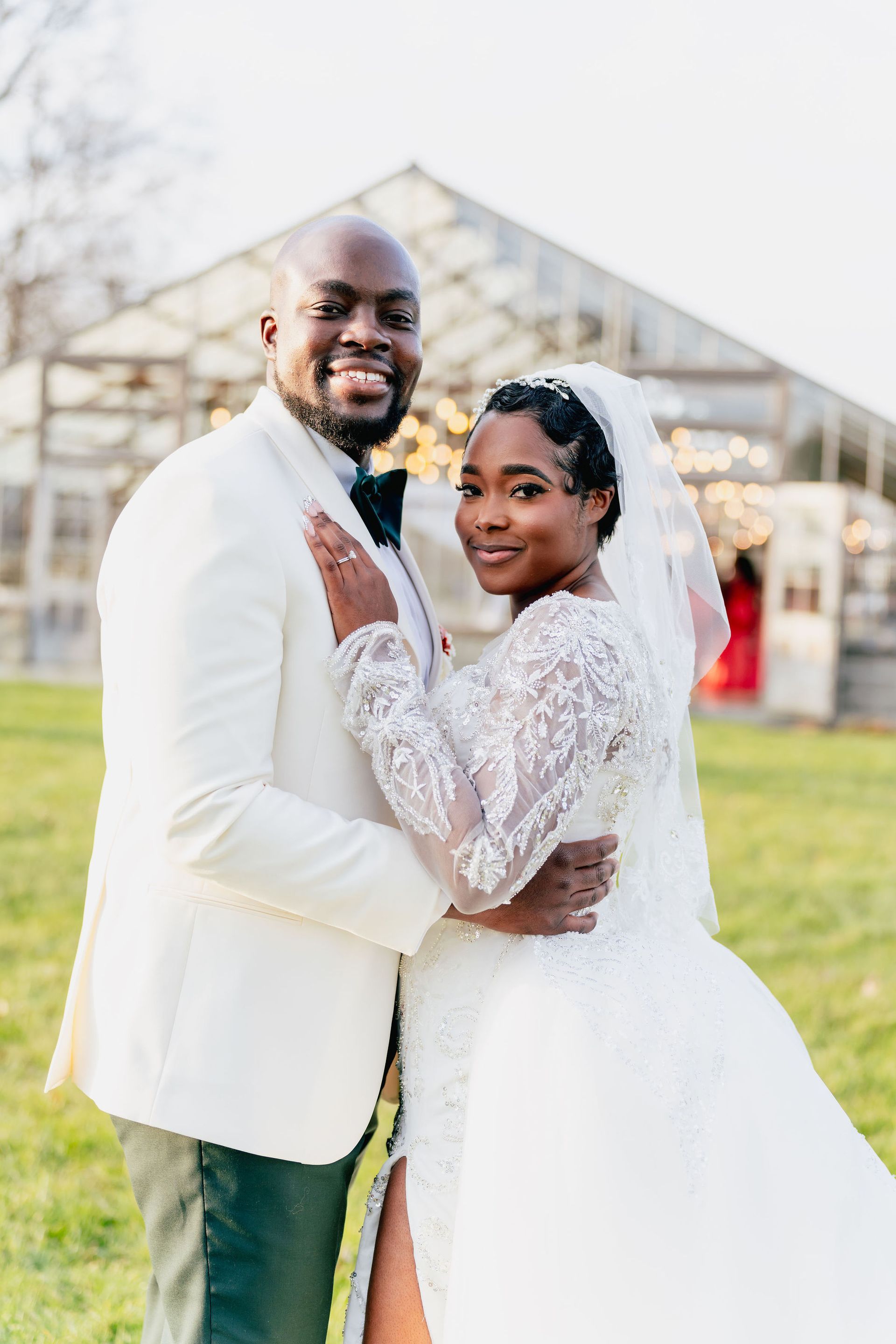 A bride and groom are posing for a picture in front of a clear tent.