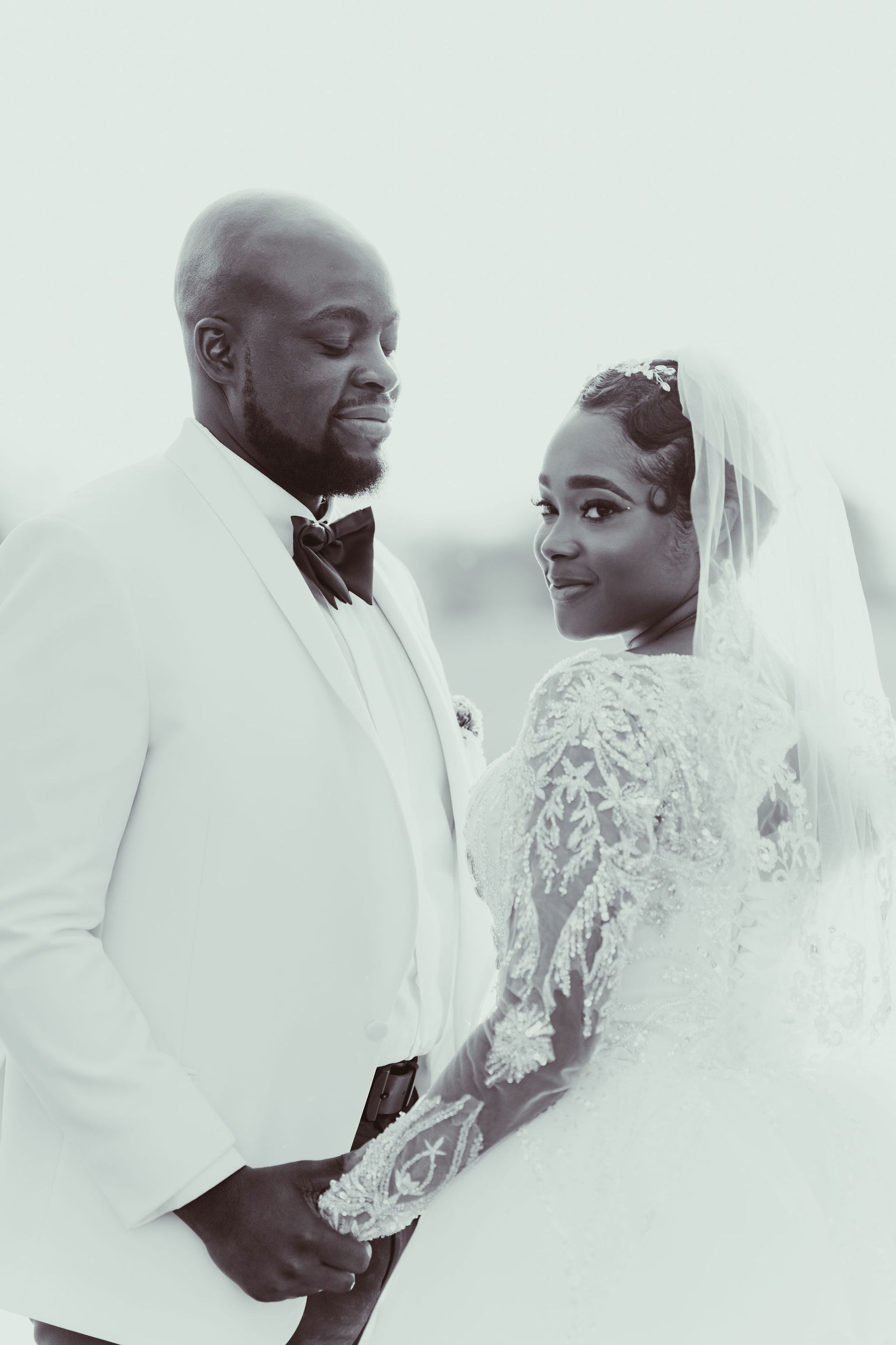 A black and white photo of a bride and groom holding hands.