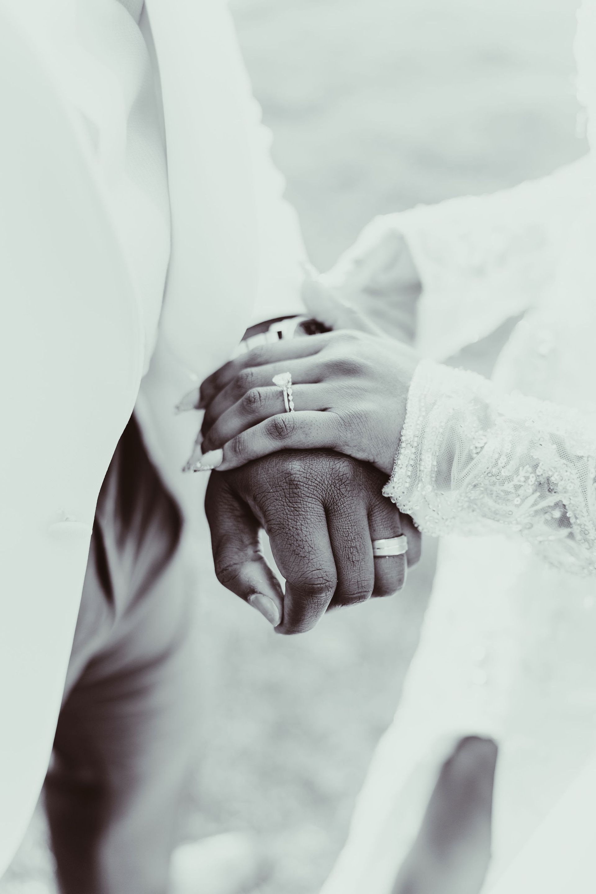 A black and white photo of a bride and groom holding hands