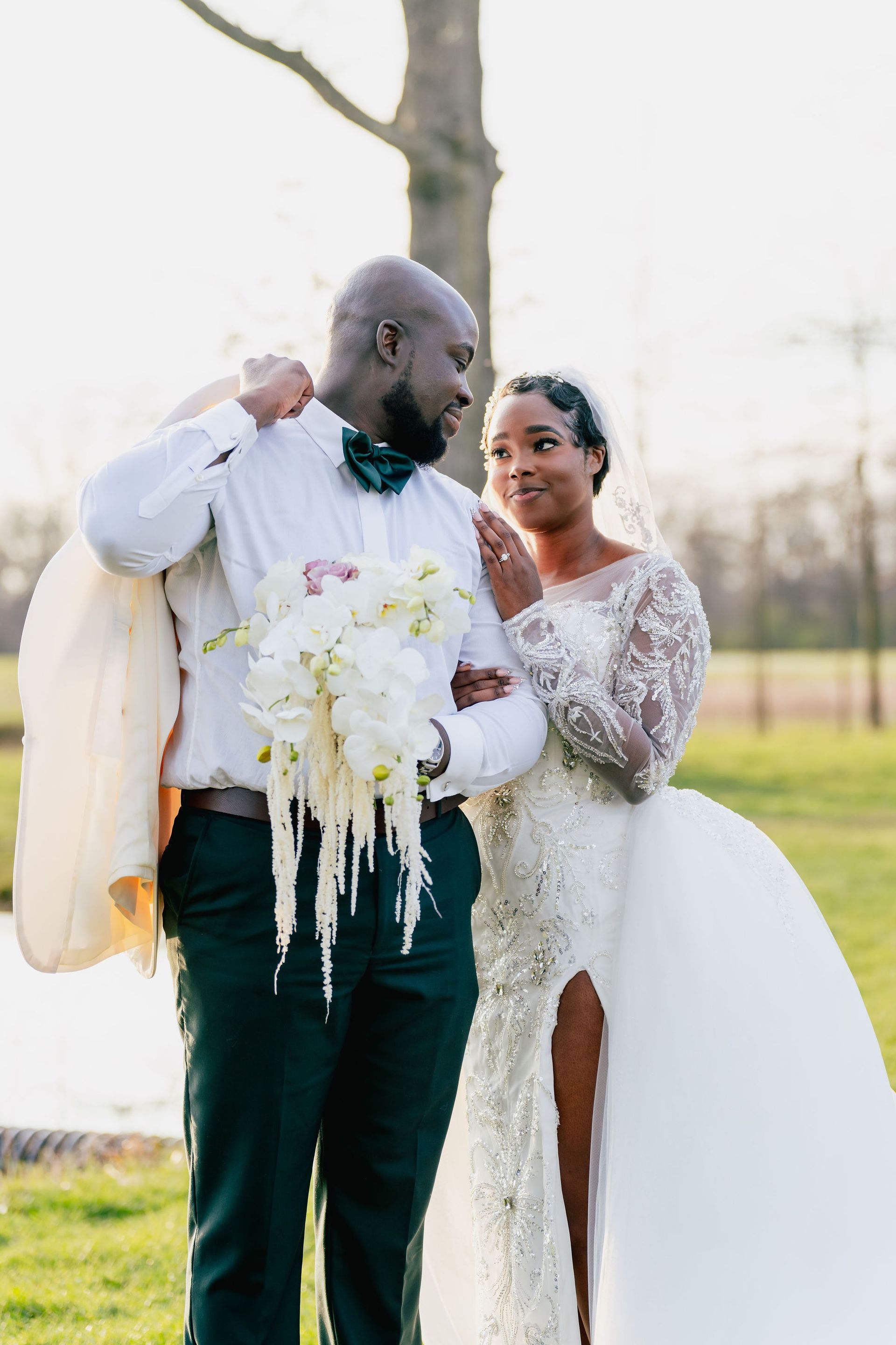 A bride and groom are standing next to each other in a field.