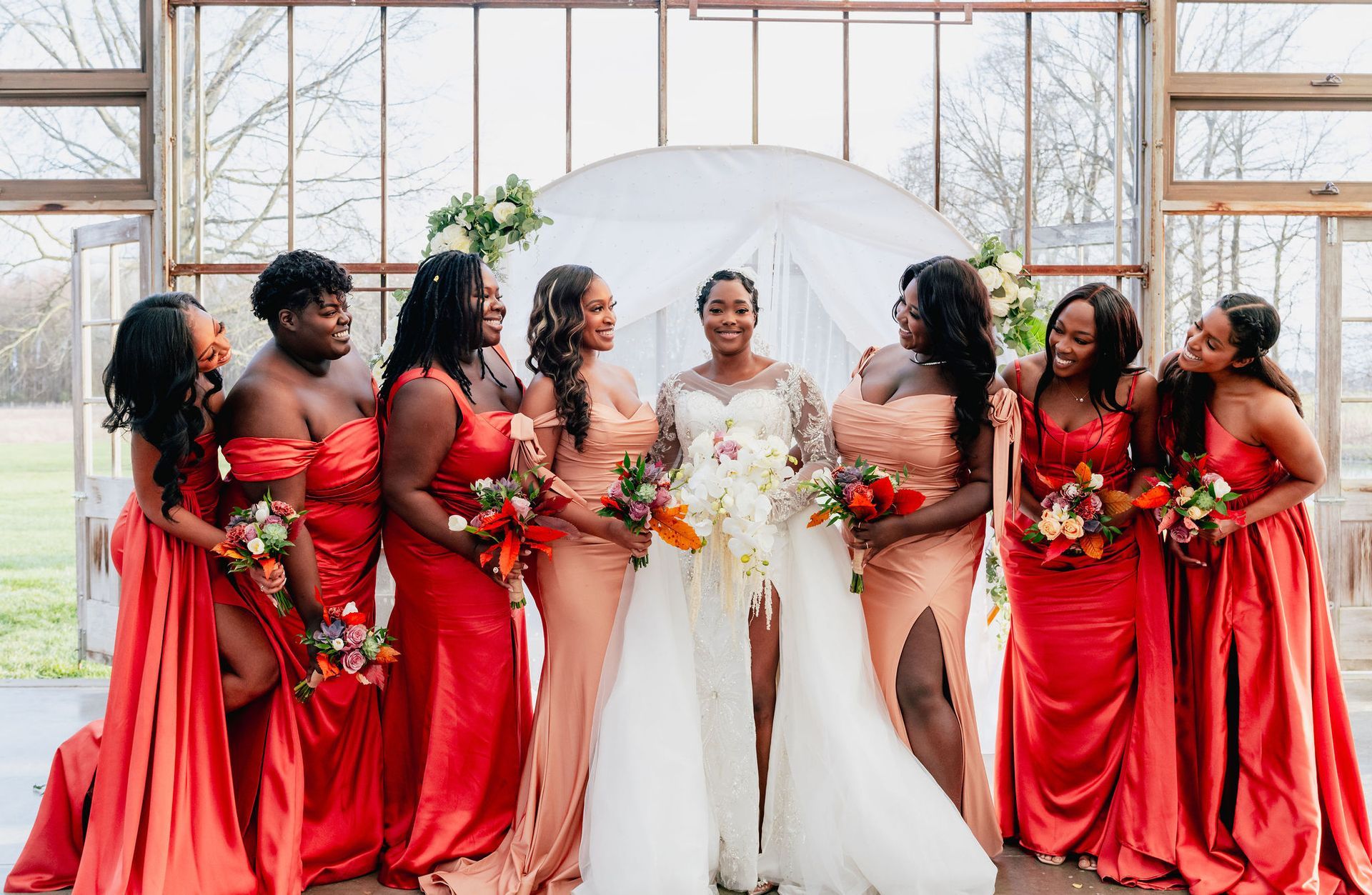 A bride and her bridesmaids are posing for a picture in a greenhouse.