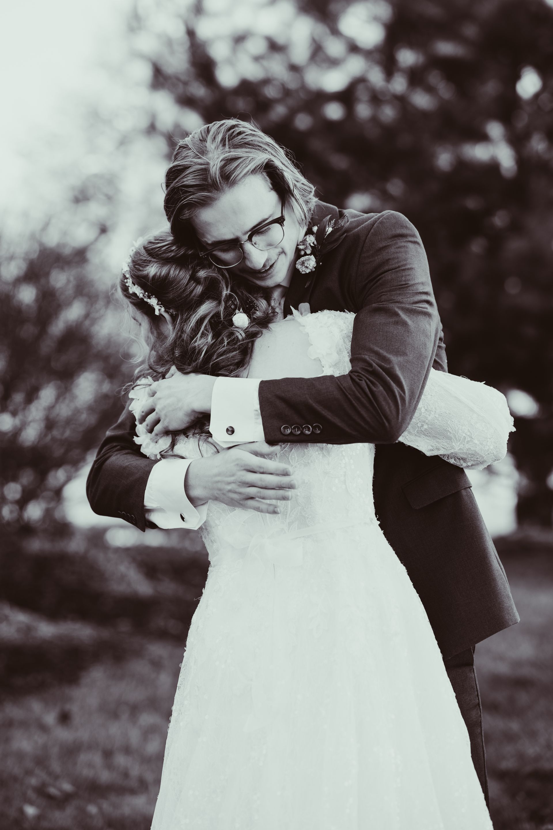 A black and white photo of a bride and groom hugging each other.