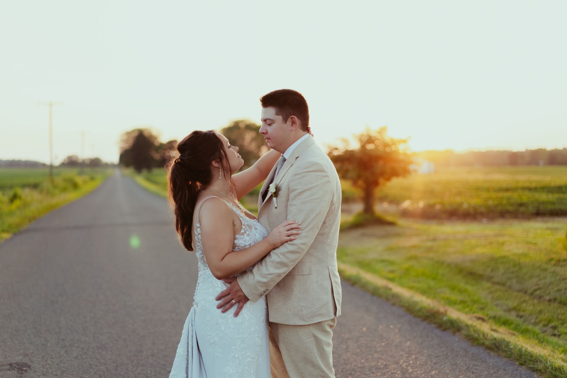 A bride and groom are standing on the side of a road at sunset at Four Seasons Barn Wedding & Event Venue.