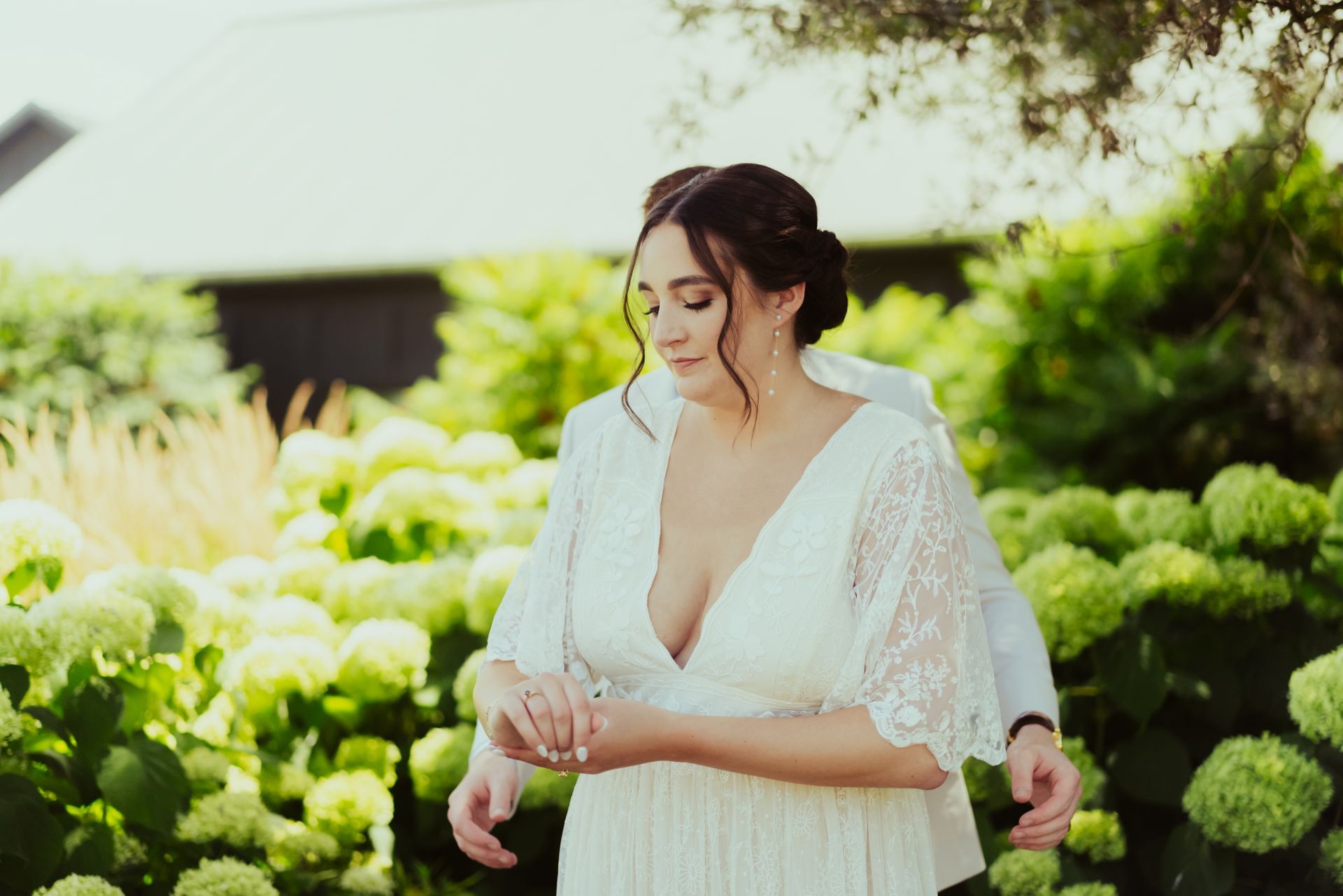 A bride in a white dress is standing next to a groom in a garden at Jorgensen Oak Grove
