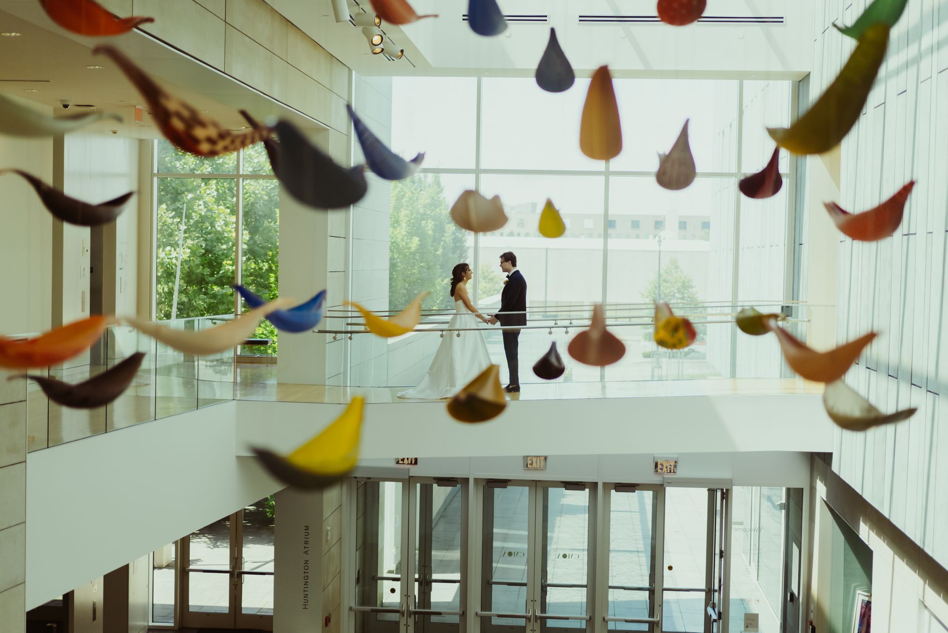 A bride and groom are standing in front of a large window in a building.
